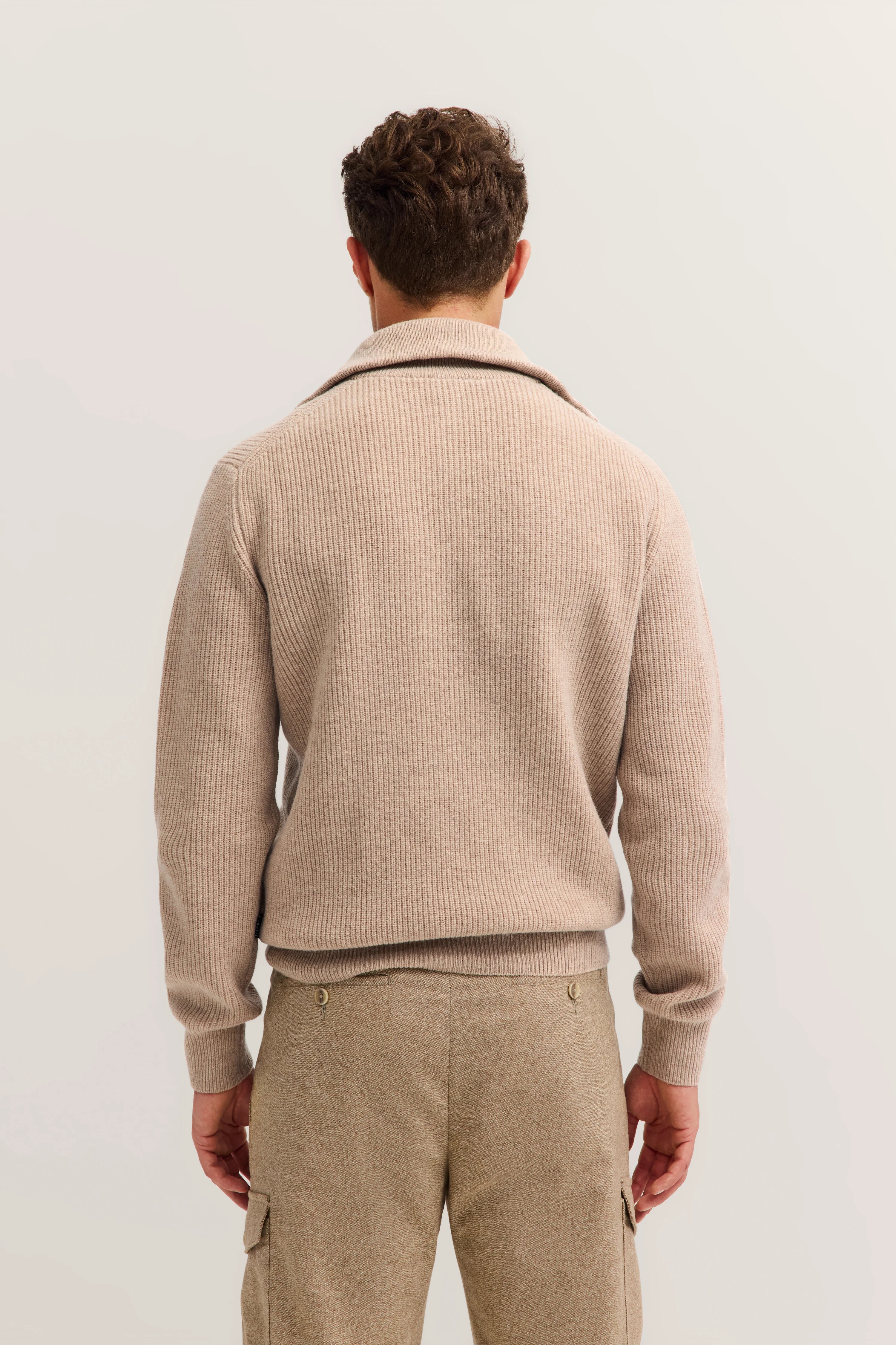 Beiger Strickpullover und beige Hose von bugatti, Rückansicht auf Model, entspanntes Stehen.