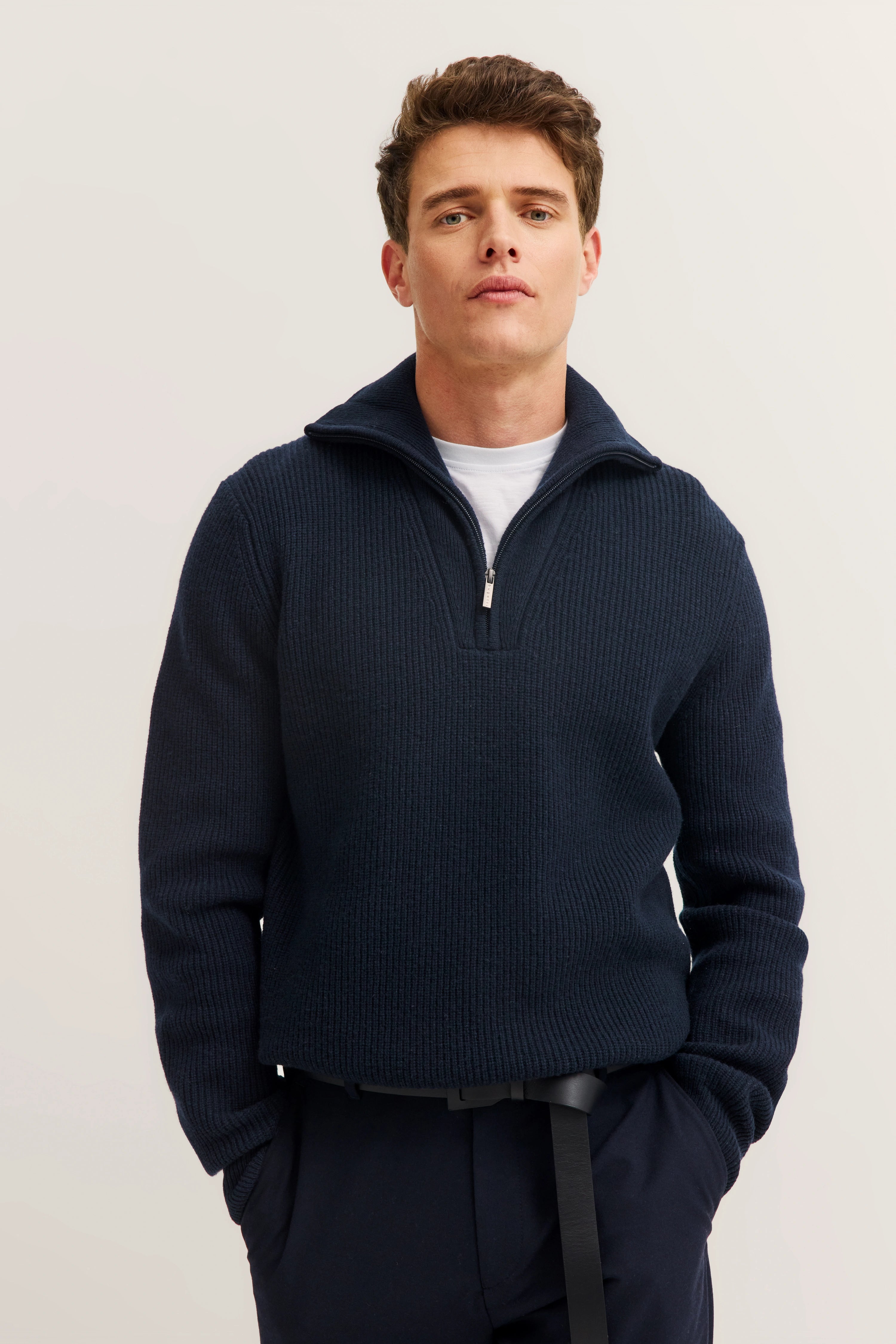 Model in navy bugatti knit sweater with zipper, casual pose, white T-shirt details visible.