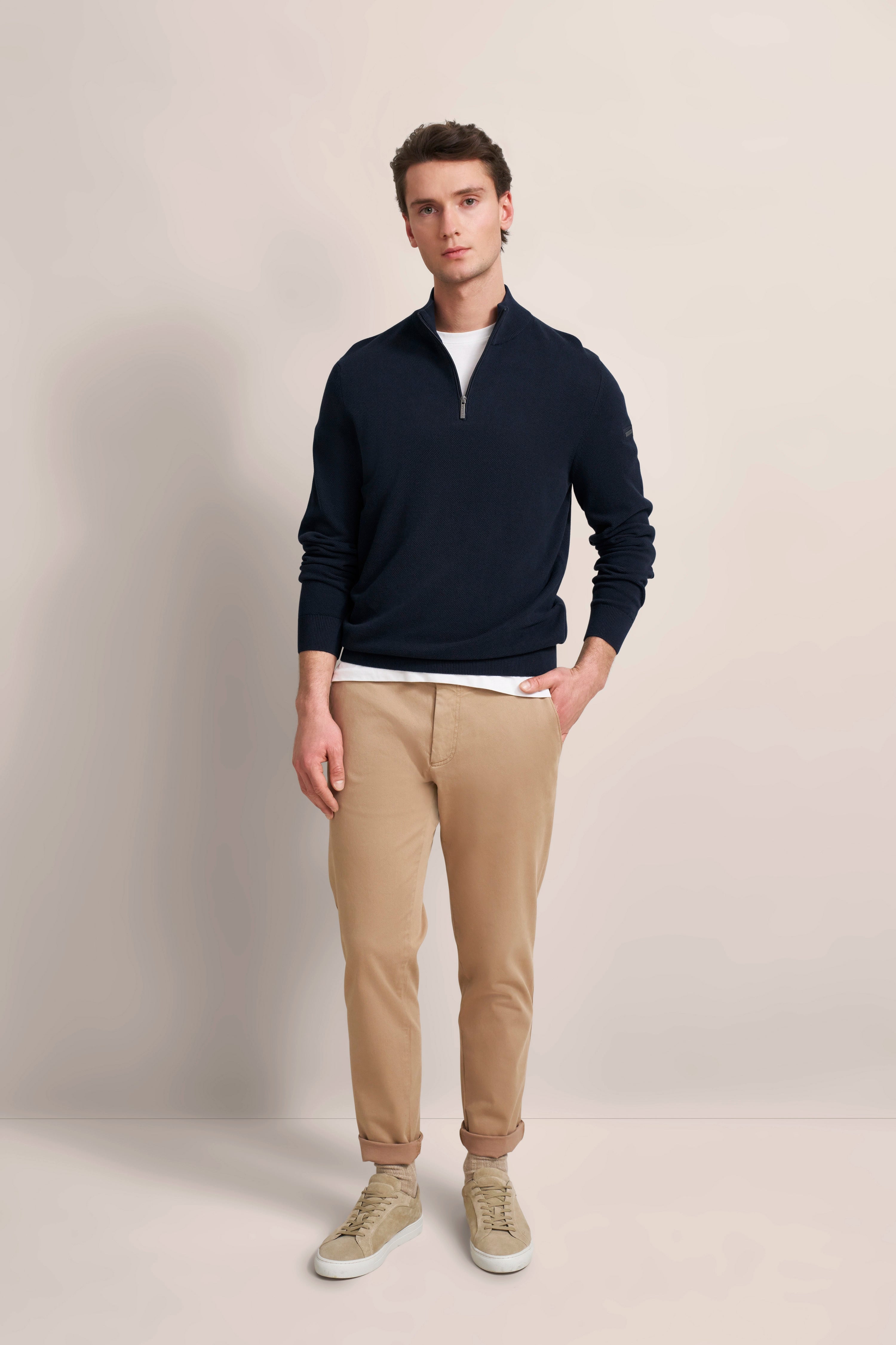 Navy pullover and beige chinos, casual model, relaxed pose.