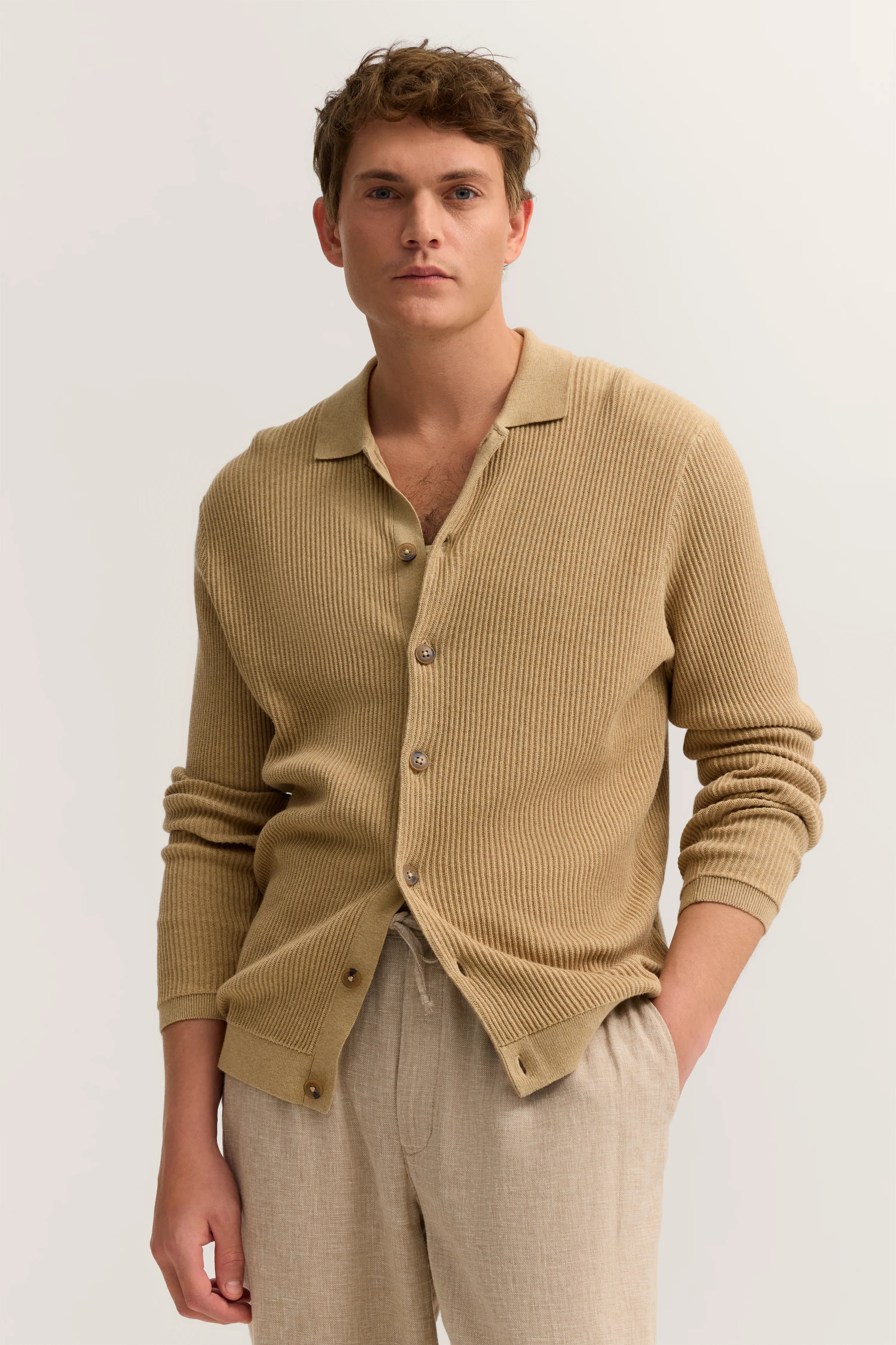 Beiger Strick-Cardigan von bugatti, leger getragen über heller Hose, Modelbild mit entspanntem Posing.