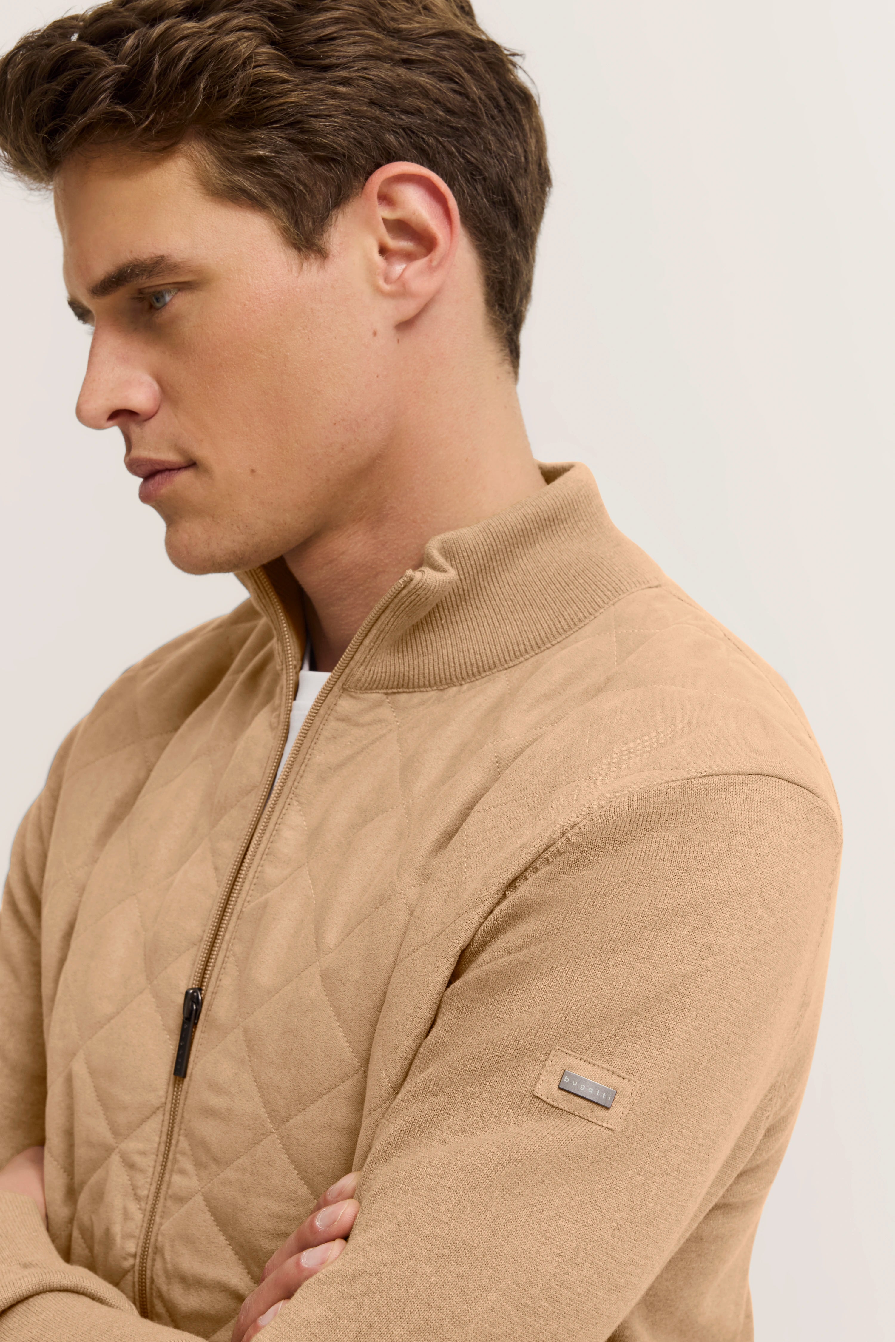 Beiger Stepp-Pullover von bugatti, Büstenfoto, seitlich verschränkte Arme, elegantes Design.