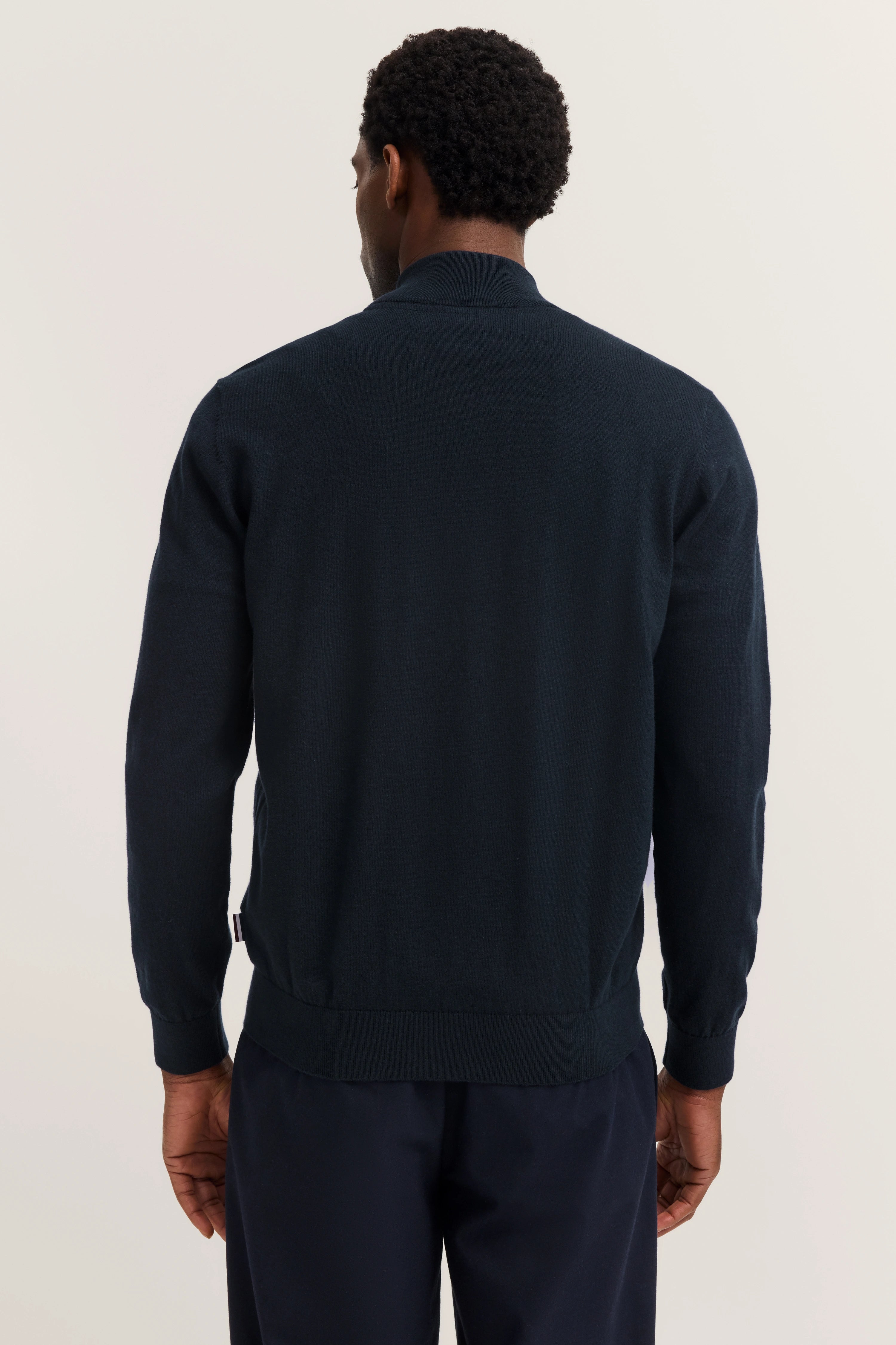 Bugatti Herrenmodell in dunkelblauem Pullover, leger von hinten fotografiert.
