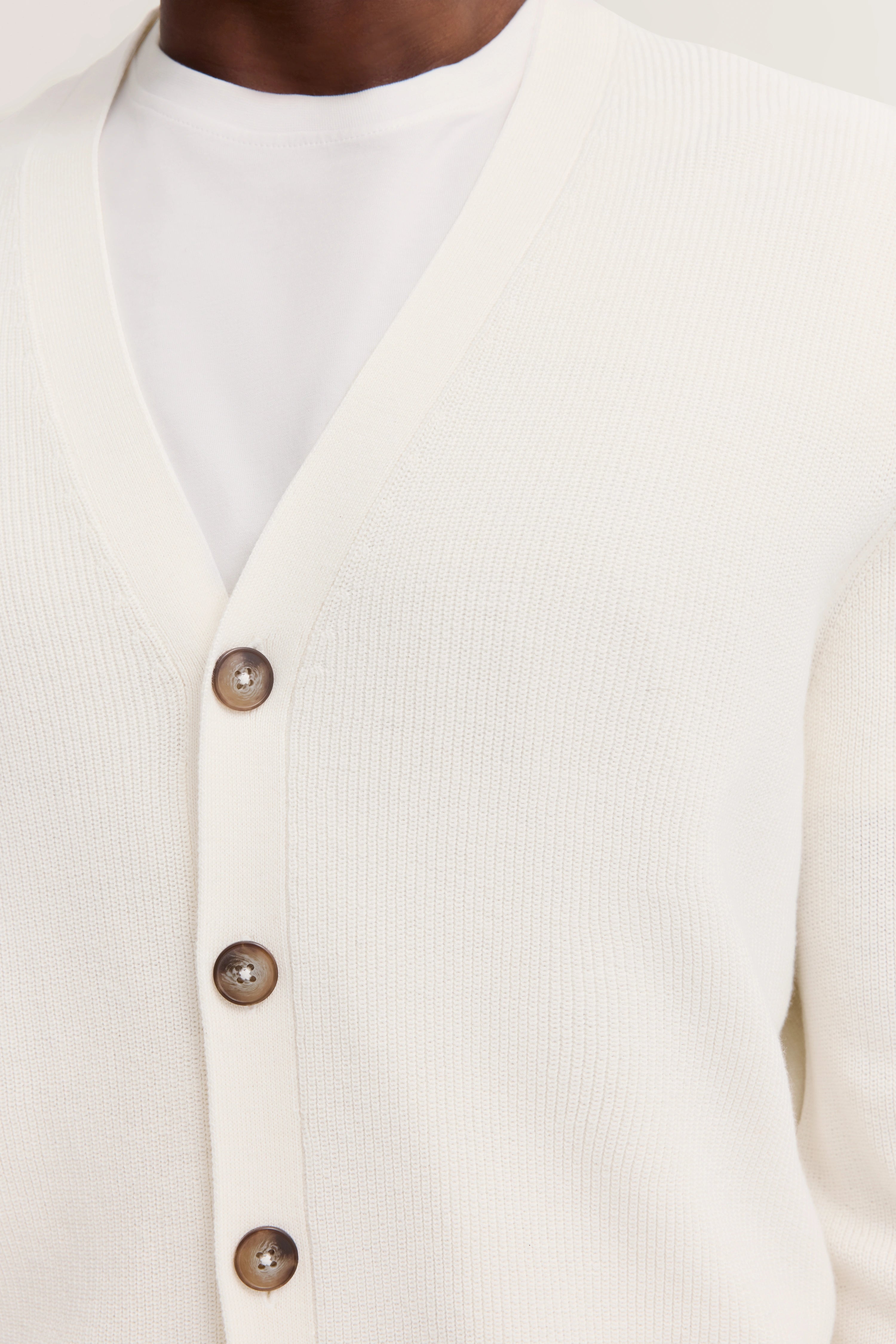 White knit cardigan with brown buttons, casual bust portrait.