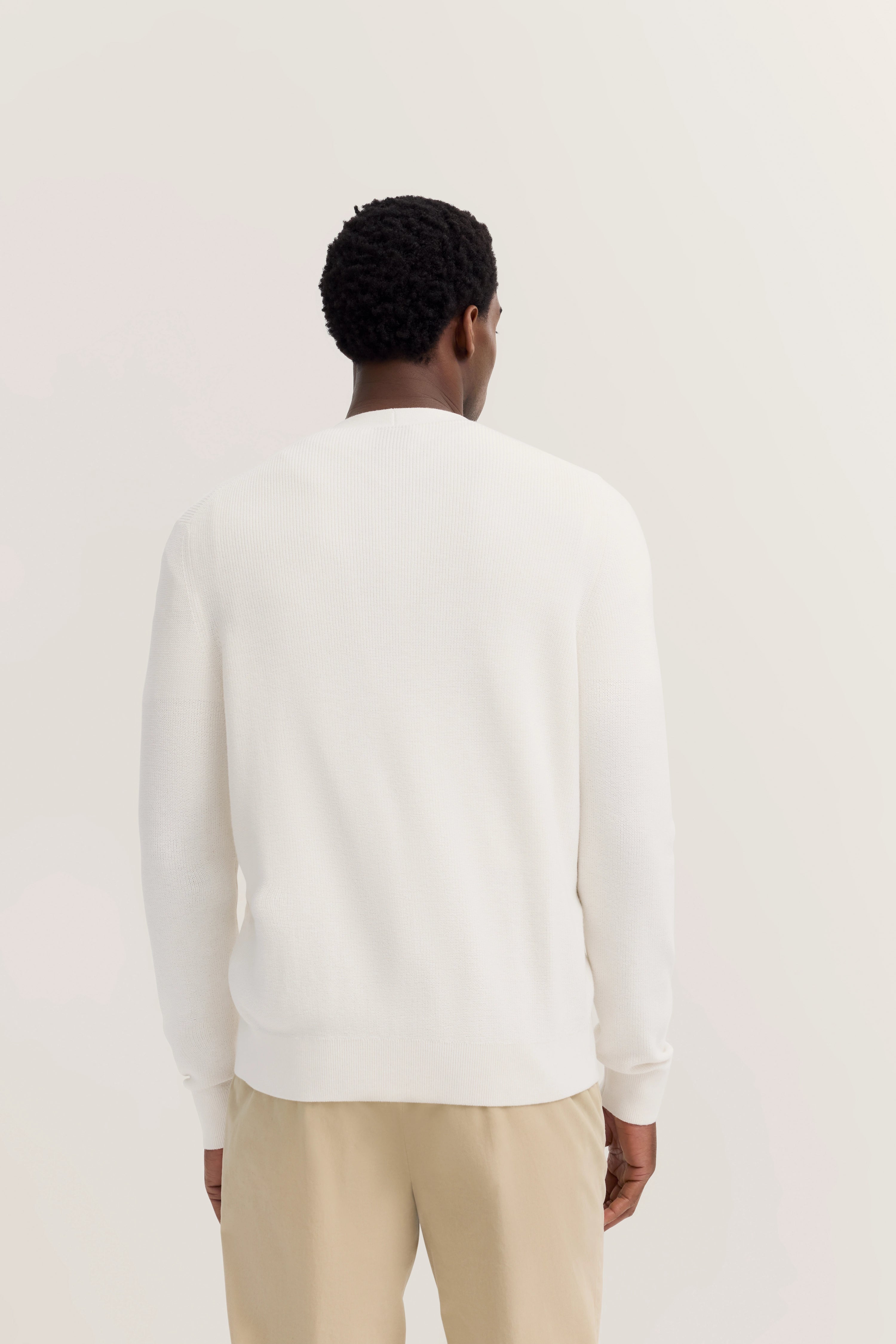 Weißer bugatti Pullover, beige Hose, Model von hinten, legeres Bild.