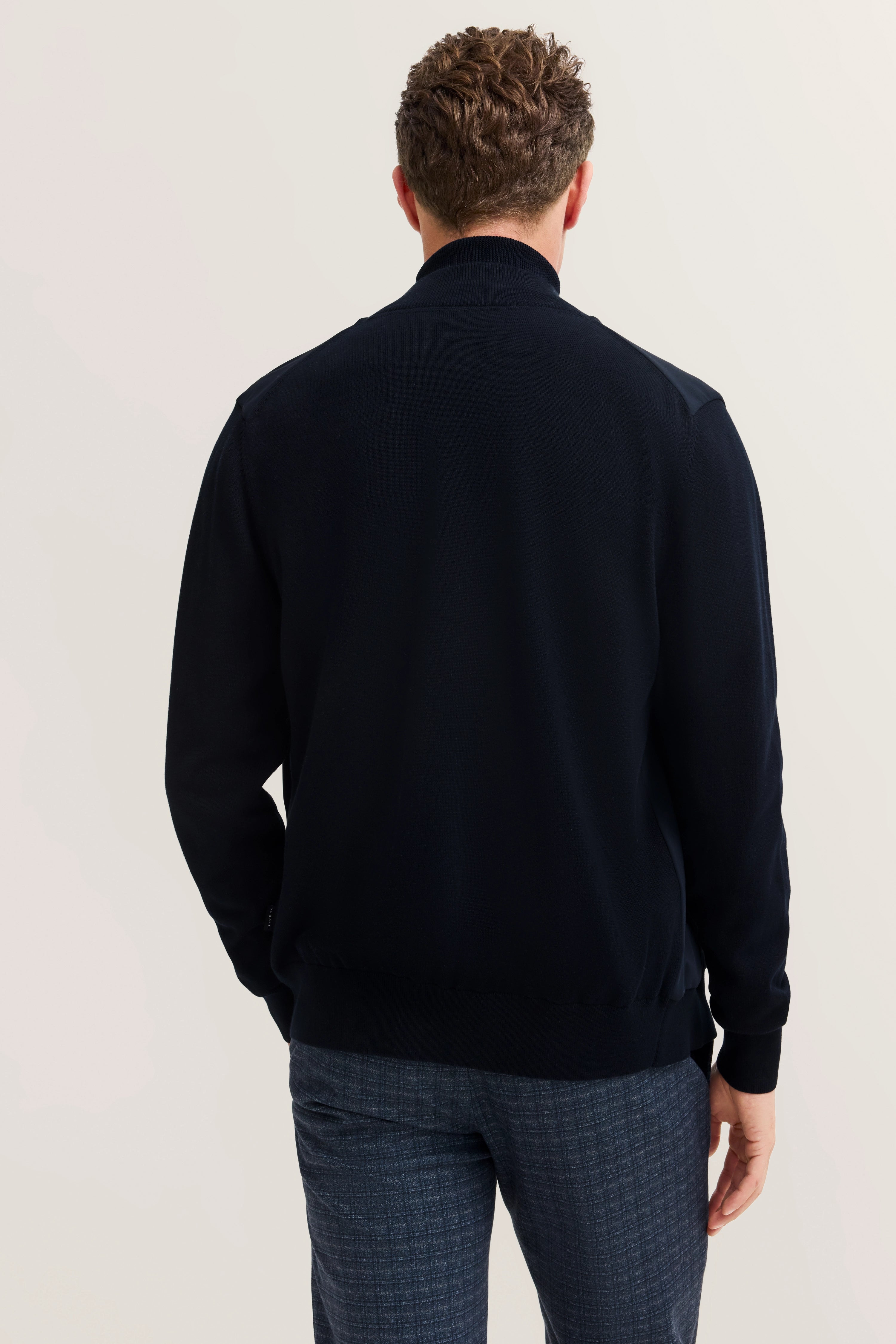 bugatti herenoutfit: Donkere jas, gemêleerde grijze broek, model van achteren gezien.