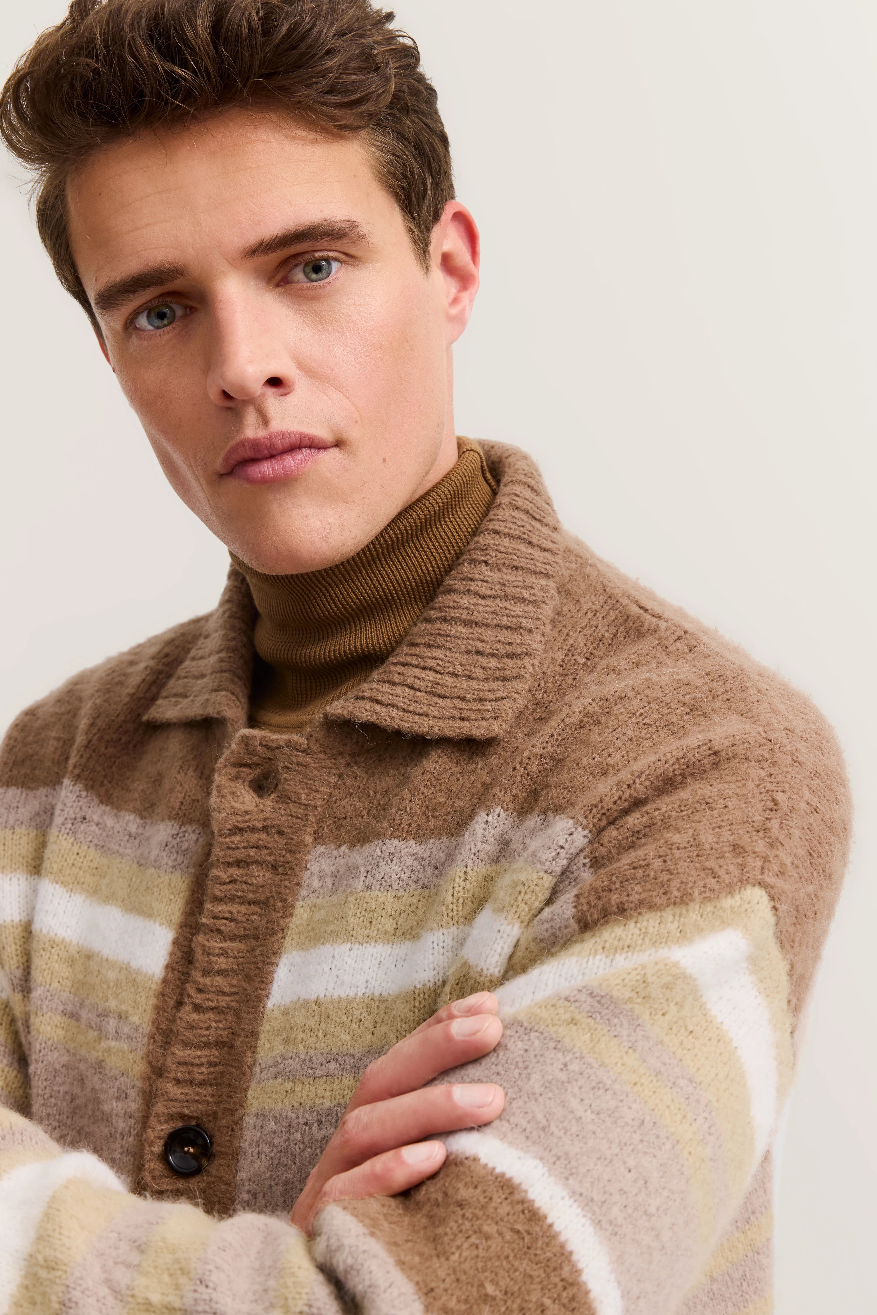 Beige striped knit top with collar, model in relaxed pose.