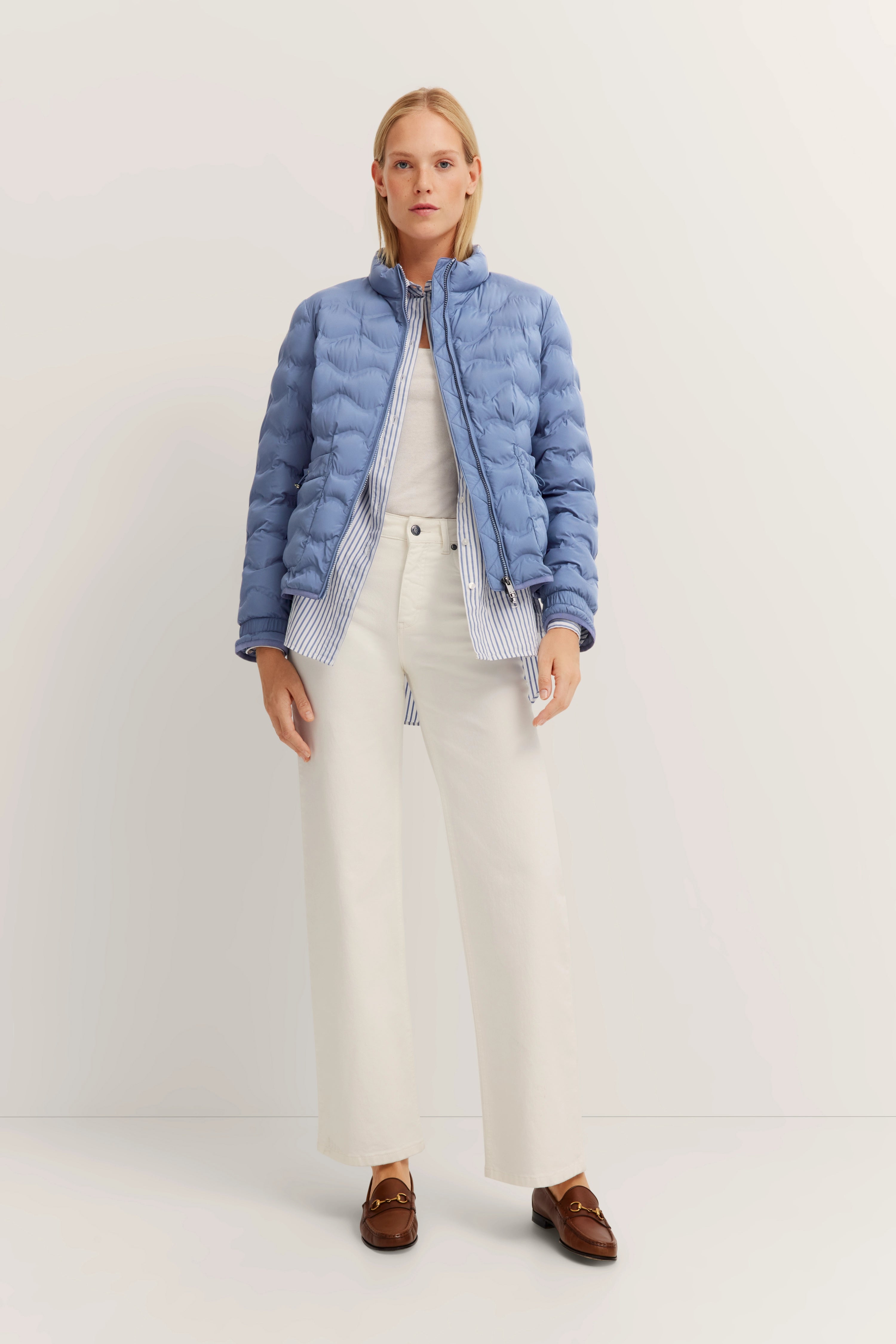 Hellblaue Steppjacke und weiße Hose, Modelbild von hinten, lässig stehend.