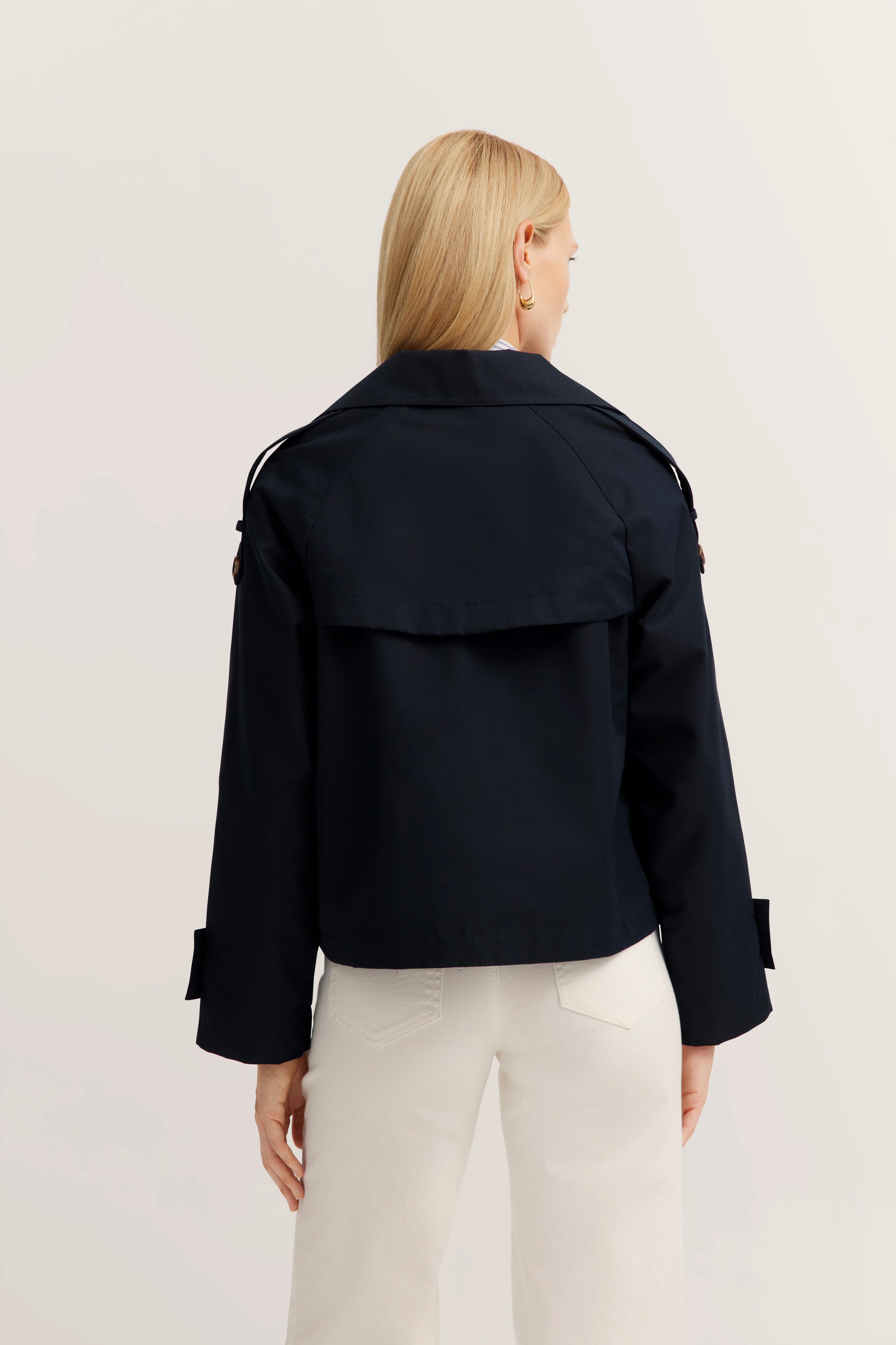 bugatti-model in marineblauw jack en witte broek, achterkant zicht.