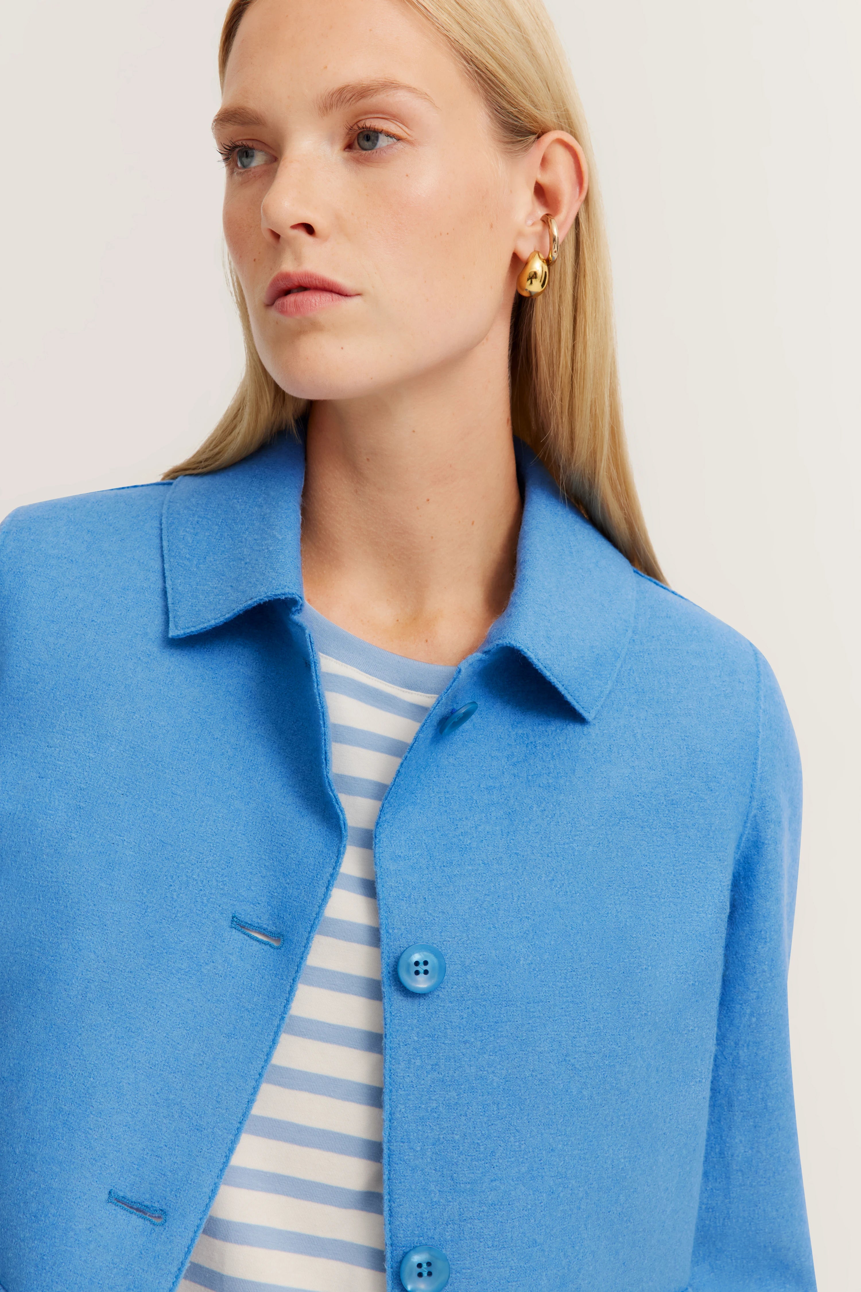 Blauw bugatti-jasje, gestreept overhemd, model kijkt opzij.