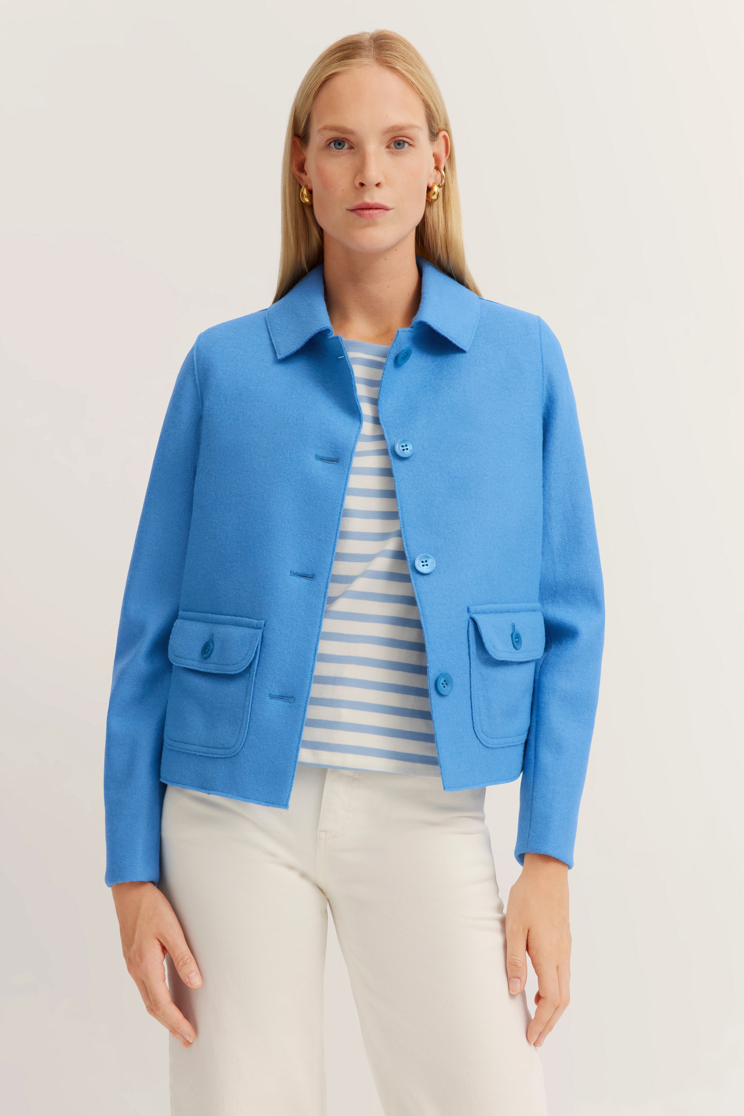 Blaues bugatti-Jackett, gestreiftes Shirt, weißer Hintergrund, Model stehend, entspannte Pose.