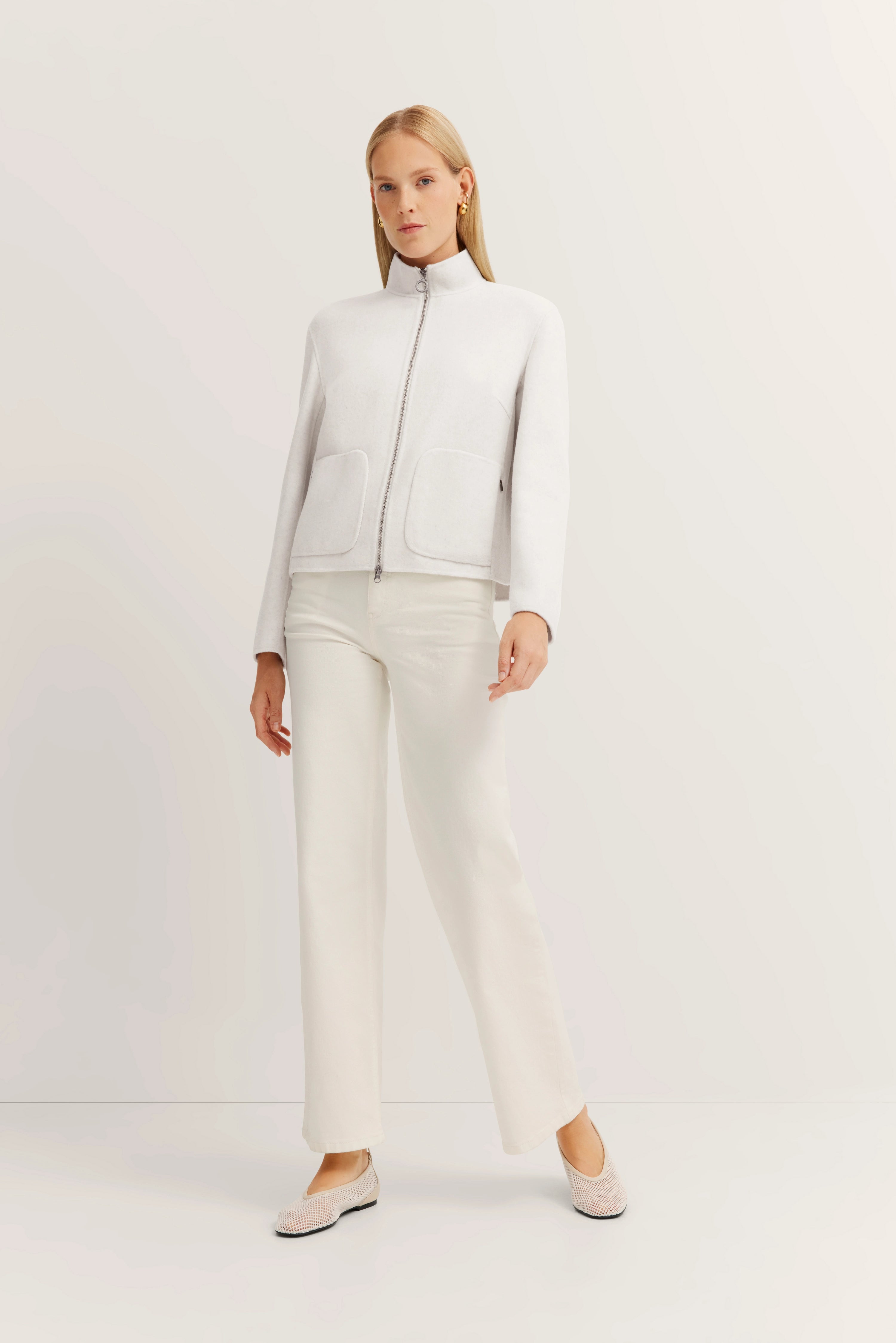 Weißes Outfit mit Jacke und Hose, Modelbild, entspannte Pose, bugatti Stil.