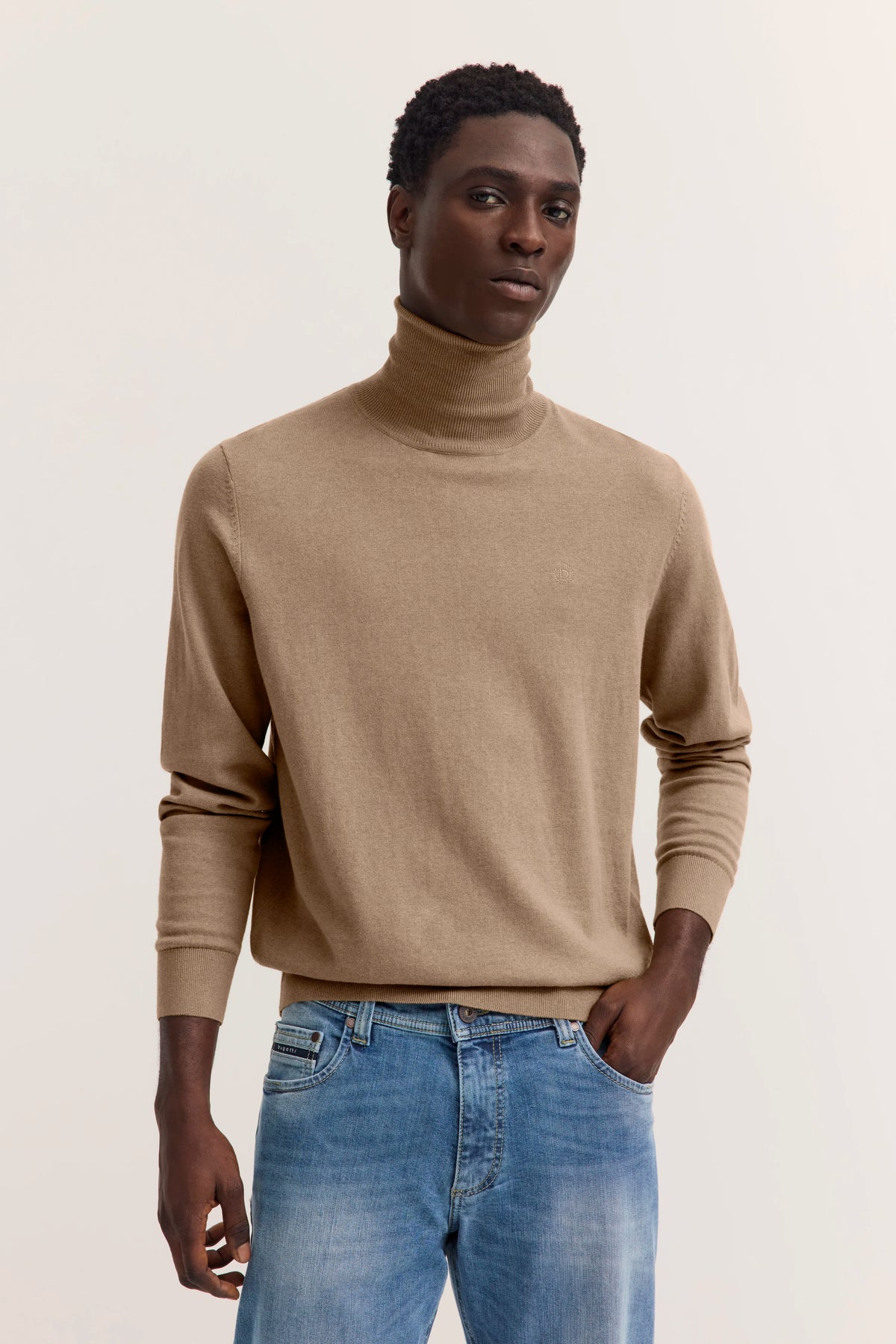 Model in beigem Rollkragenpullover und blauen Jeans, lässige Pose, bugatti.