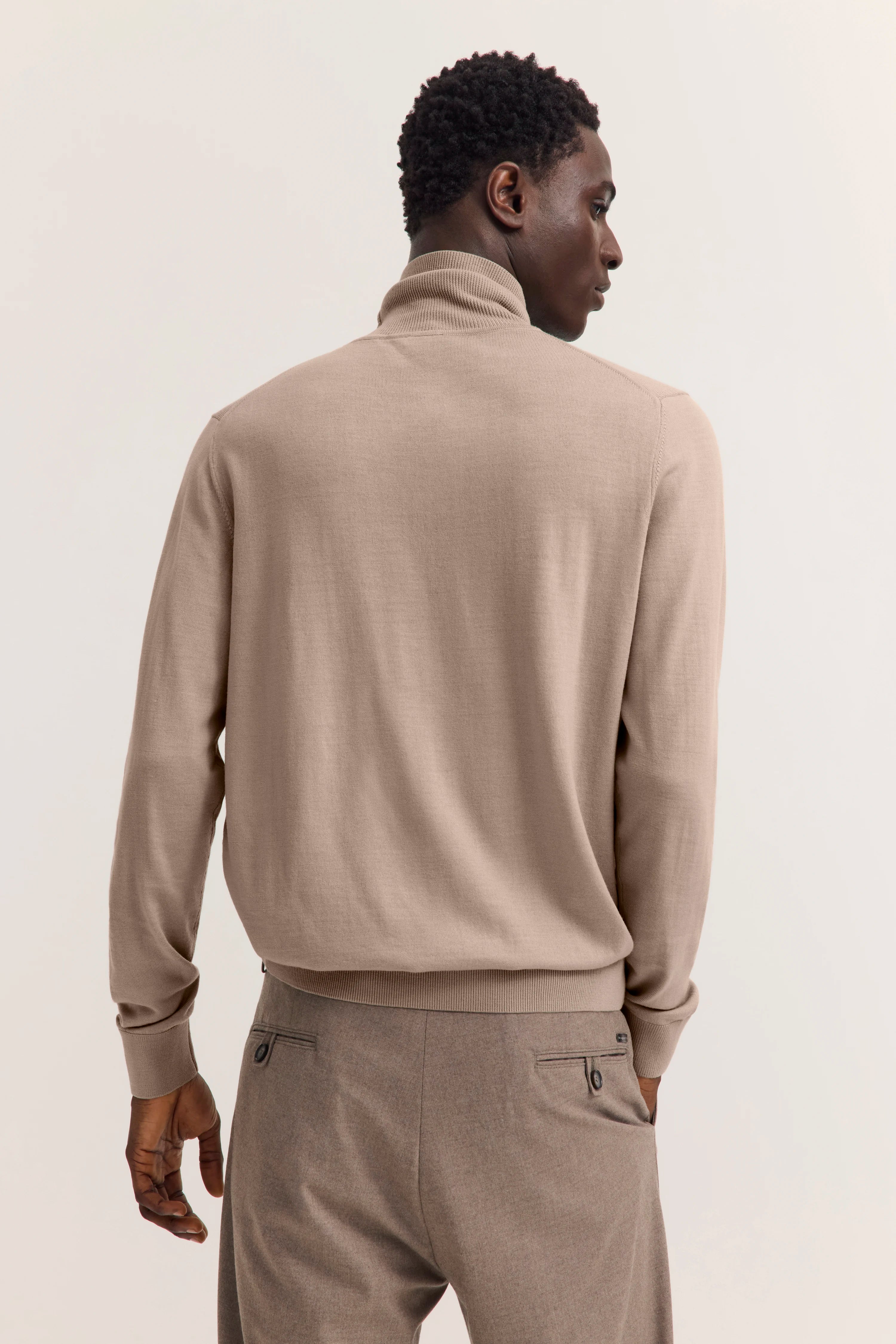 Beiges bugatti Rollkragenpullover auf Model von hinten, entspannte Pose.