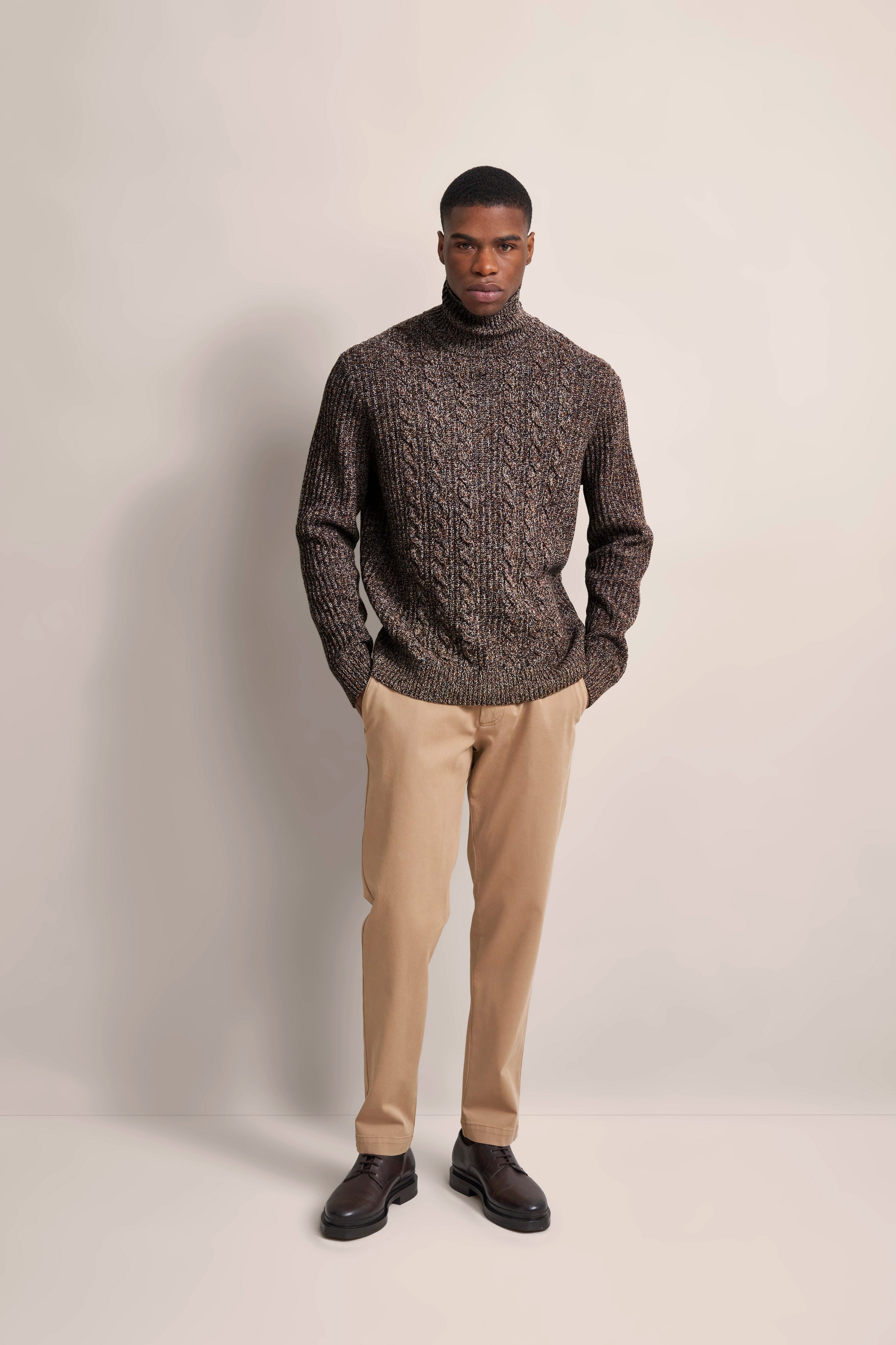 Model in brown knit sweater and beige pants, casual pose, bugatti style.