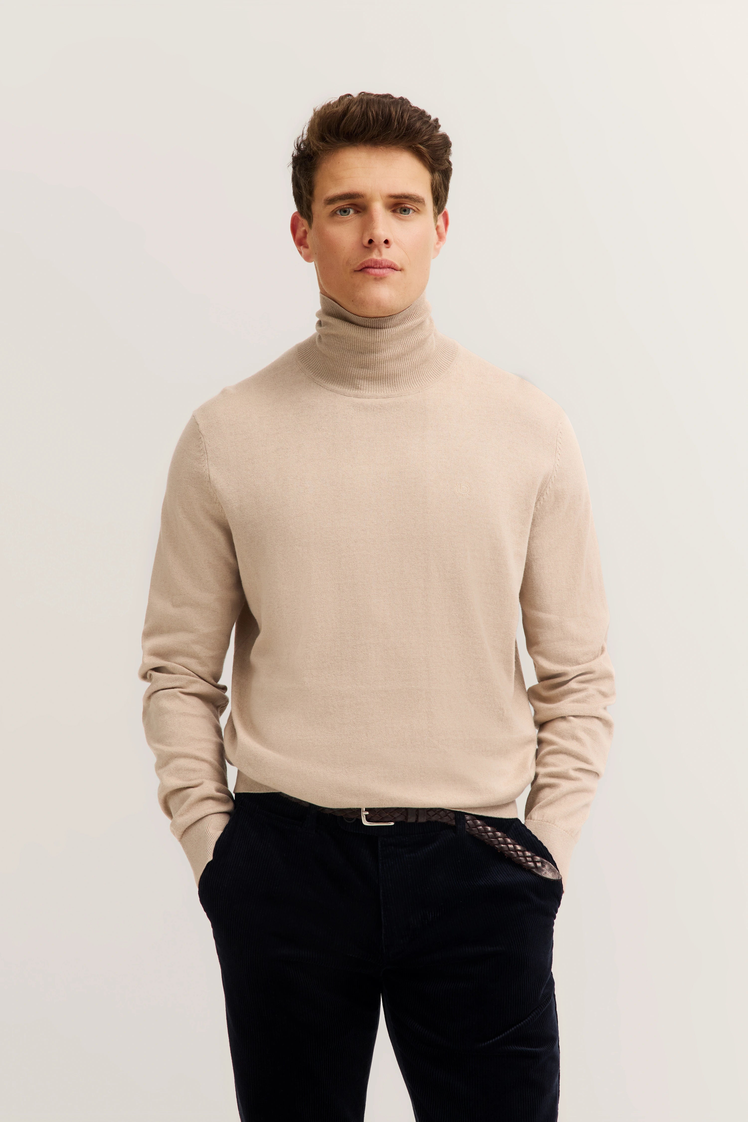 Beige turtleneck sweater, black pants, casual pose, embodies bugatti's refined, timeless elegance and Italian inspiration.