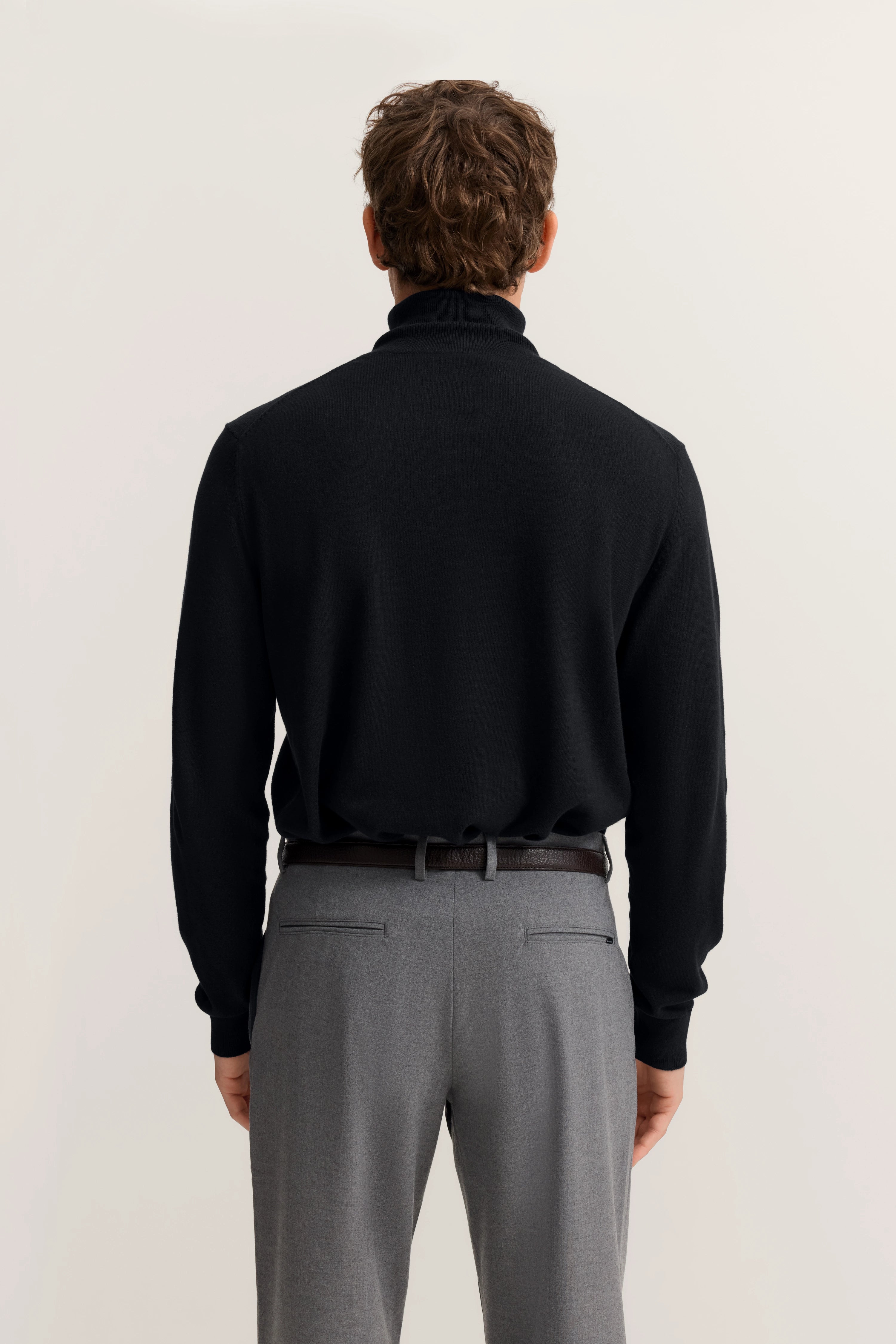 Rückansicht: Schwarzer bugatti Rollkragenpullover, graue Hose, legeres Modelbild.