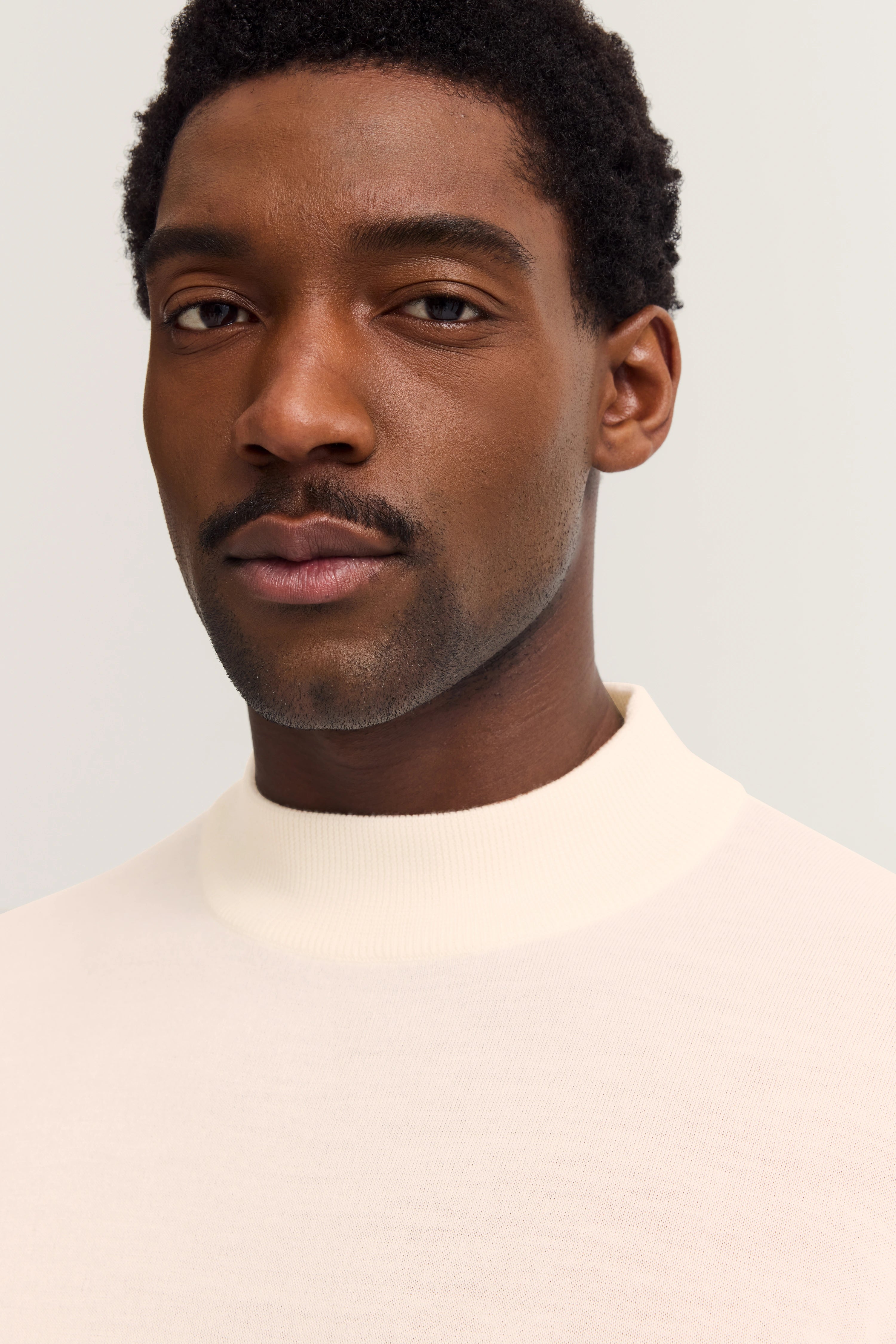 Büstenbild eines Mannes im cremefarbenen bugatti Rollkragenpullover, stilvoll und zeitlos elegant.