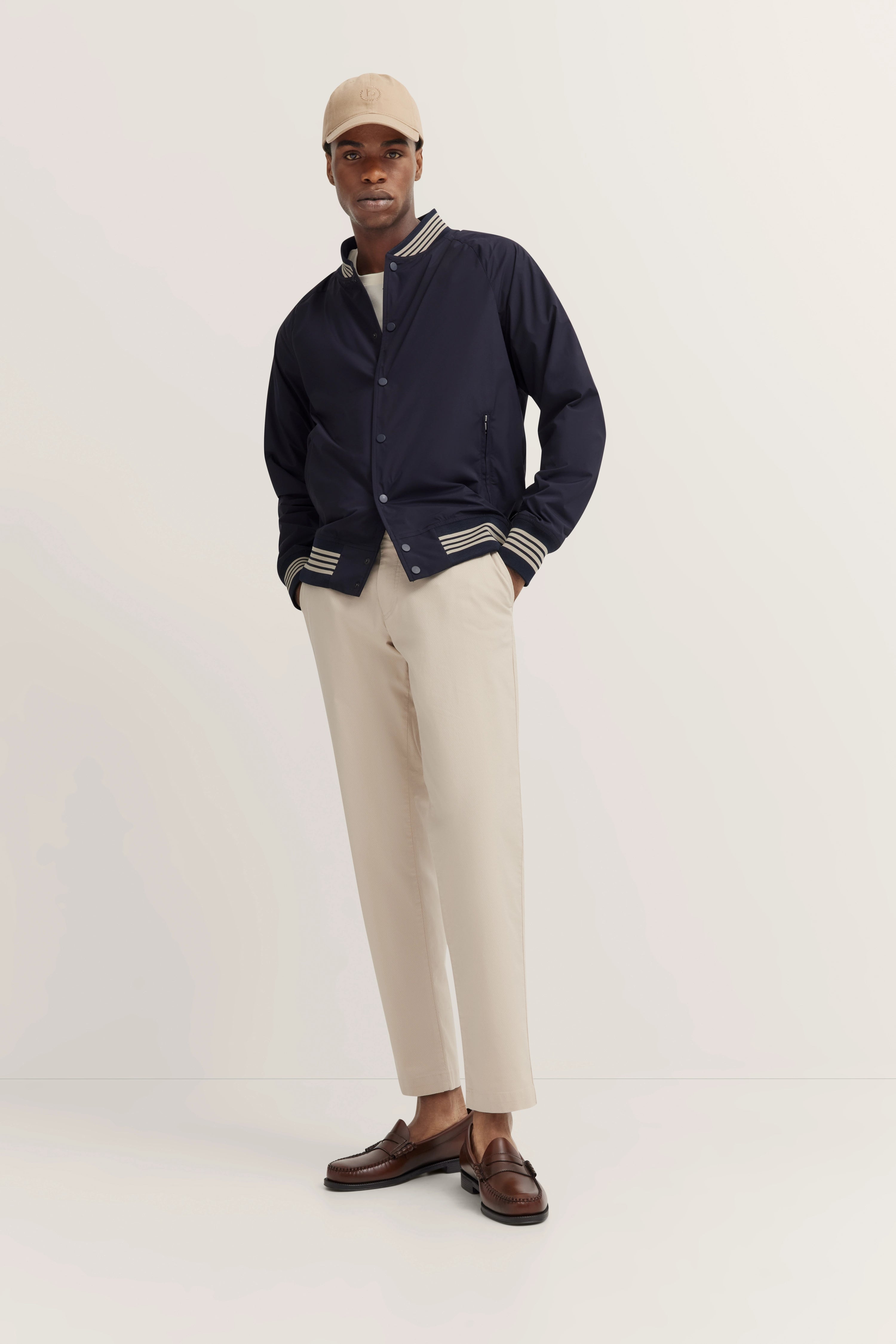 Navy Jacke, beige Hose, braune Schuhe, beige Mütze auf Model