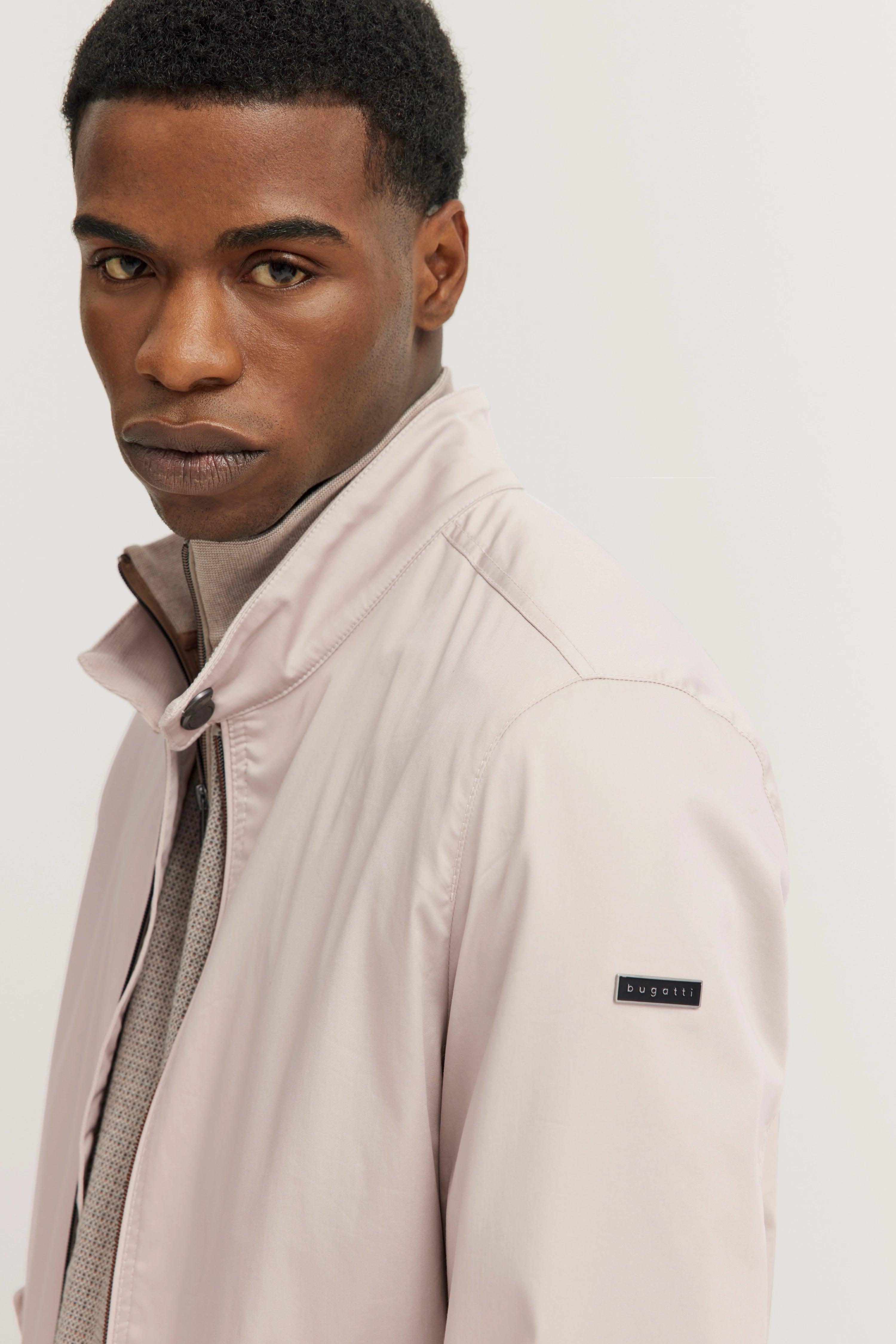 Model in beiger bugatti Jacke, legeres Posing, eleganter und zeitloser Stil.