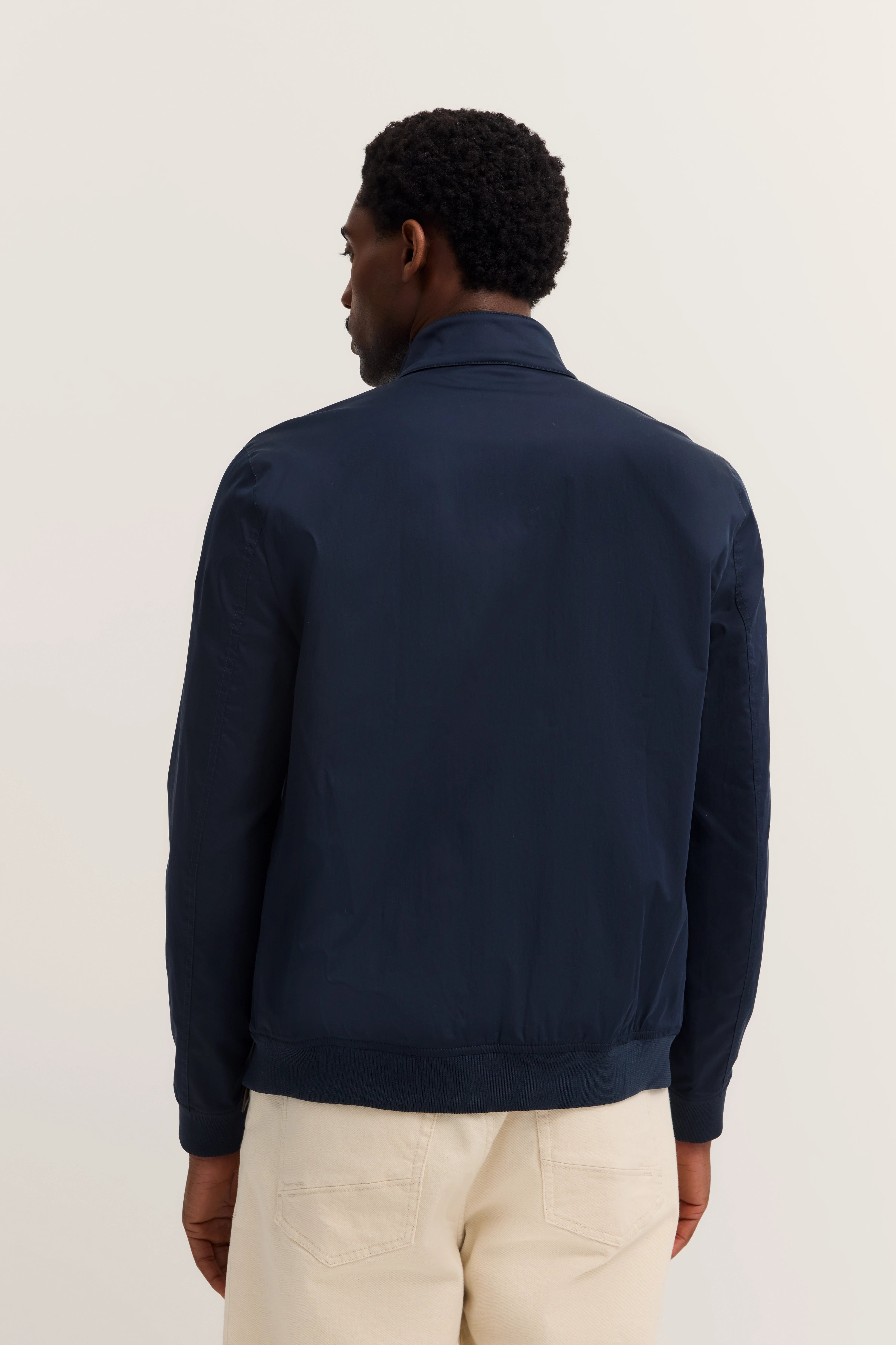 bugatti men's dark blue jacket, back view. Styled with light pants, casual pose.