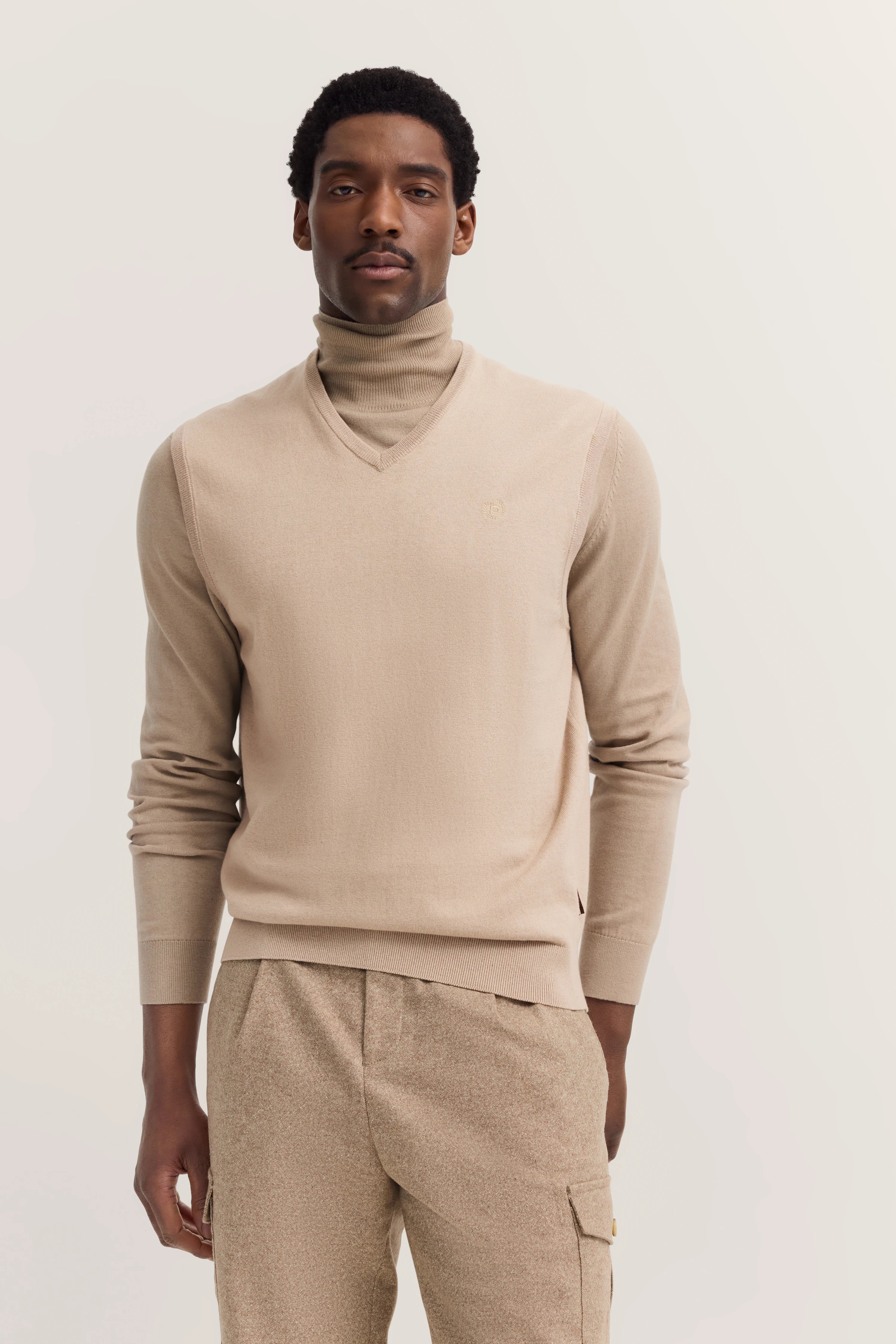 Beiger Rollkragenpullover und Hose, Modelbild, entspanntes Posing, stilvoll und elegant von bugatti.