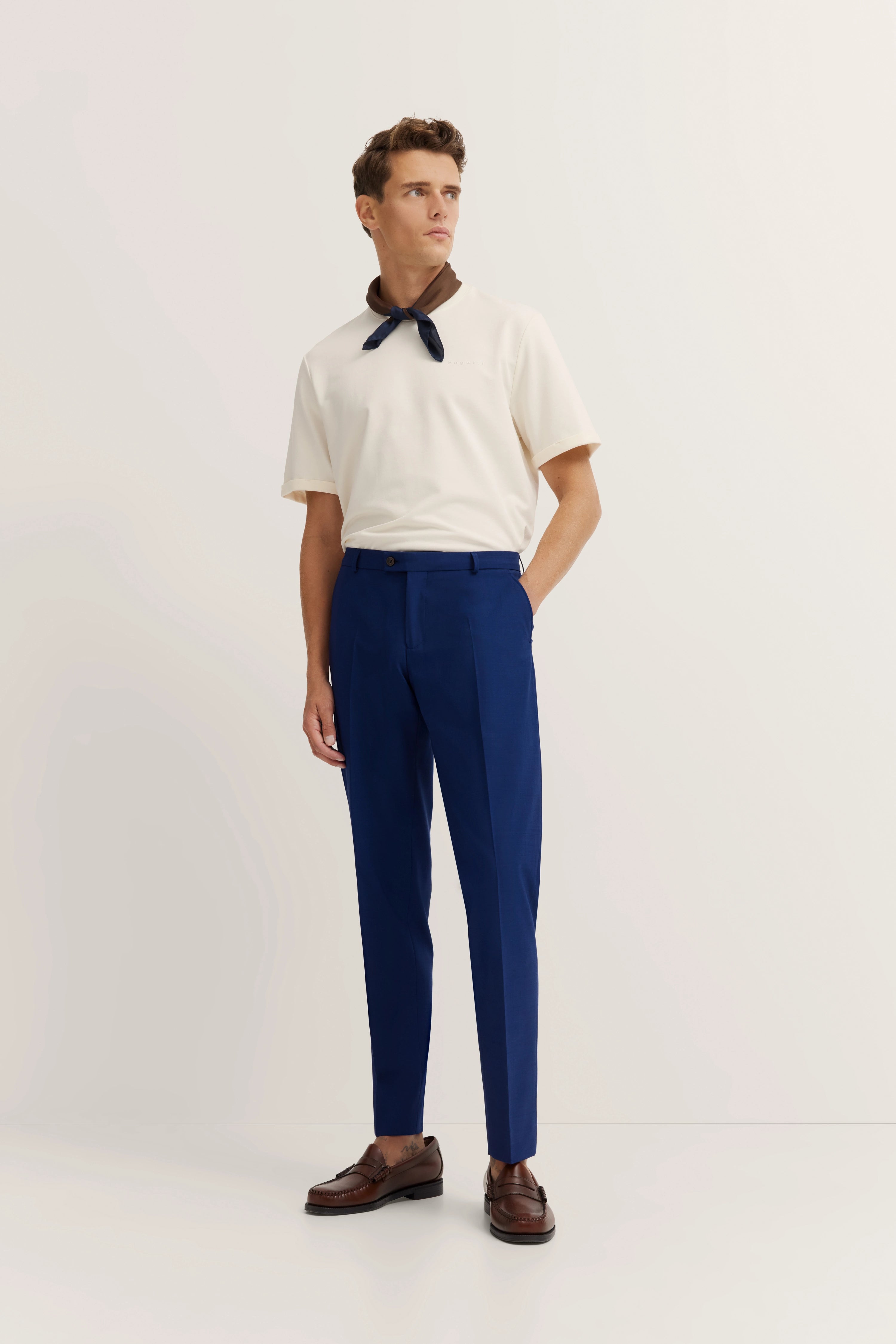 Model in cream t-shirt, blue pants, brown loafers, embodying bugatti's timeless elegance and Italian-inspired style.