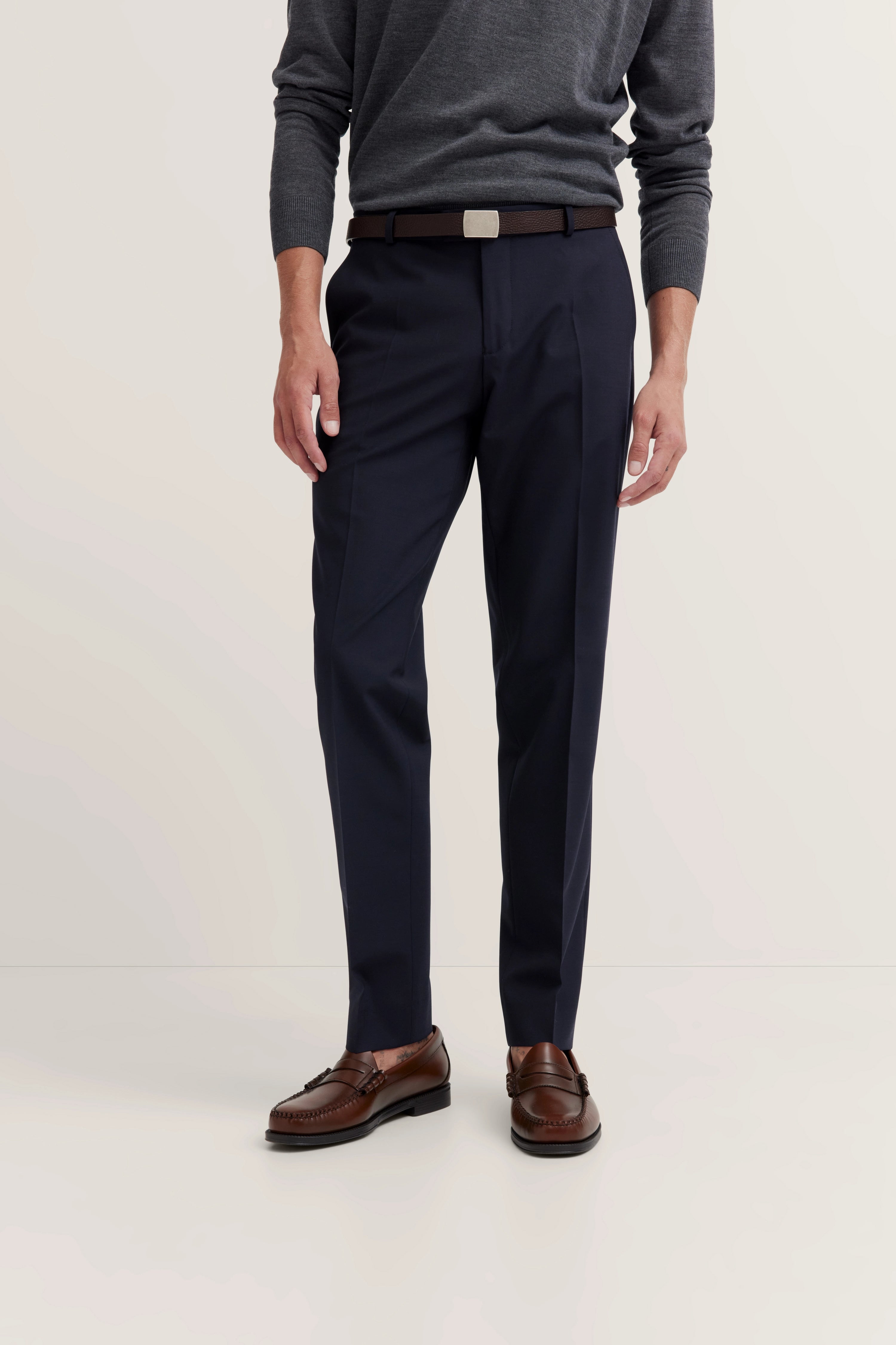 Grauer Pullover, blaue Hose, brauner Gürtel, braune Schuhe