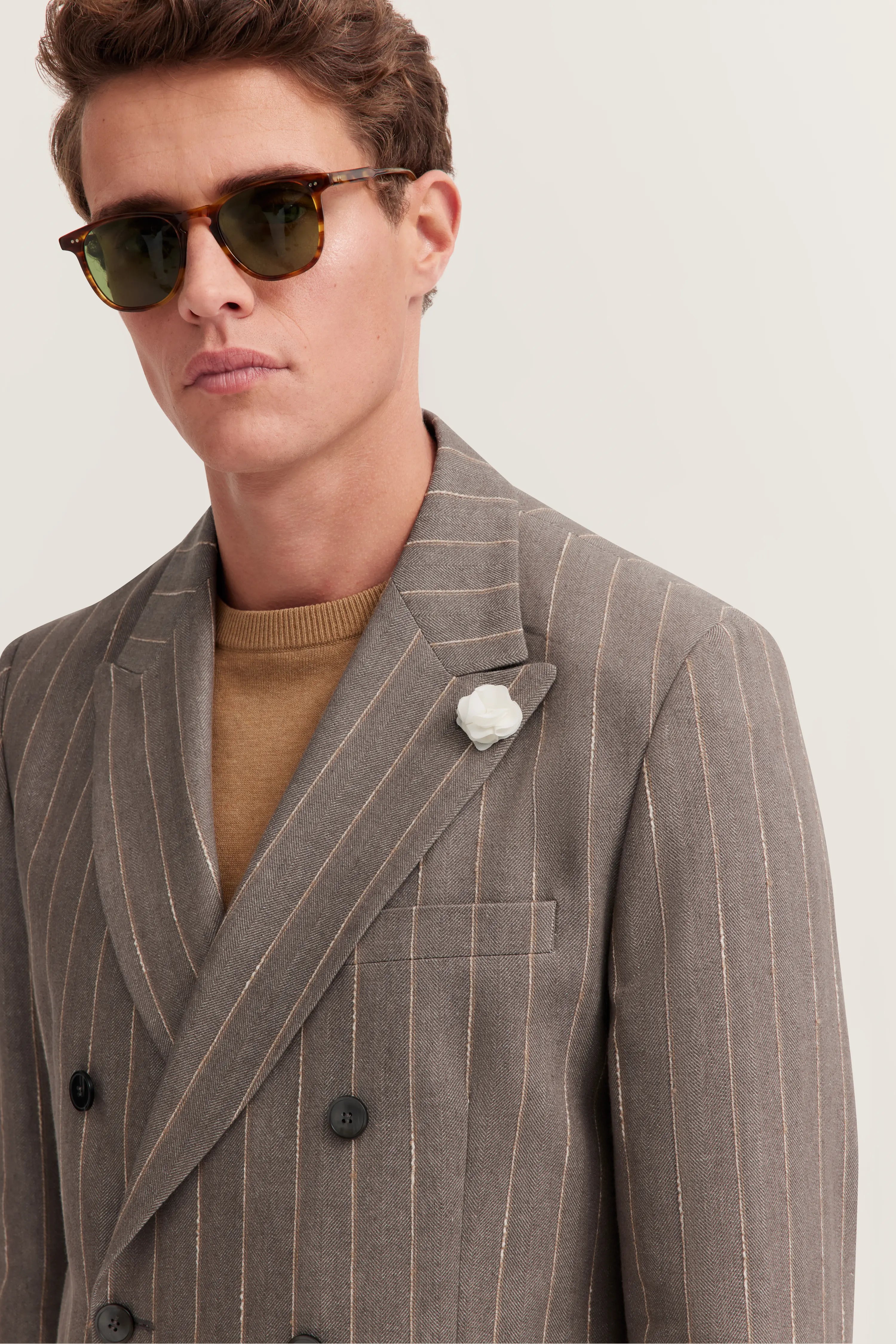 Grauer Nadelstreifen-Blazer, beiges Shirt, Model mit Sonnenbrille, Halbprofil-Pose.