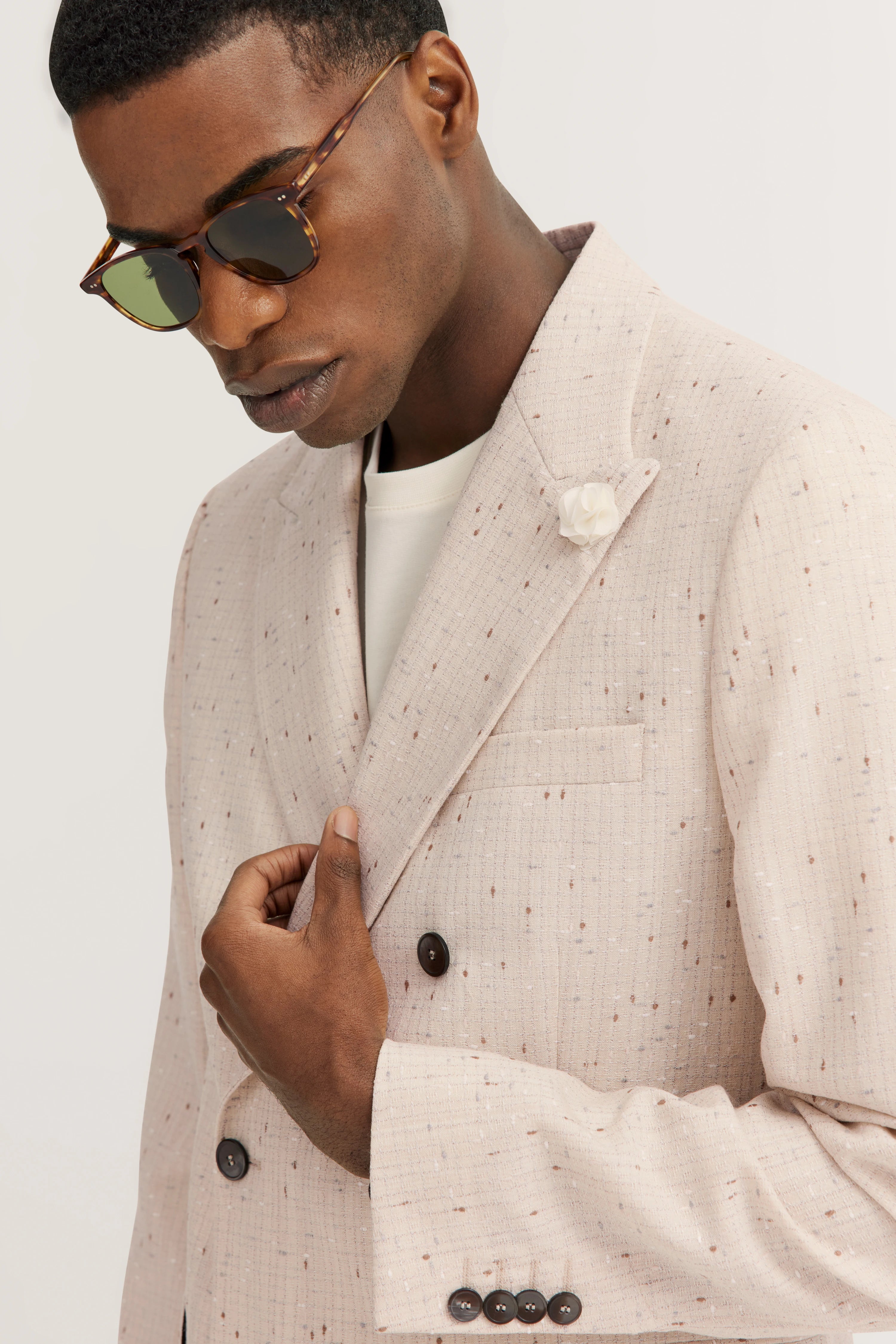 Model in een crèmekleurige, gestippelde bugatti-blazer, elegant poserend.