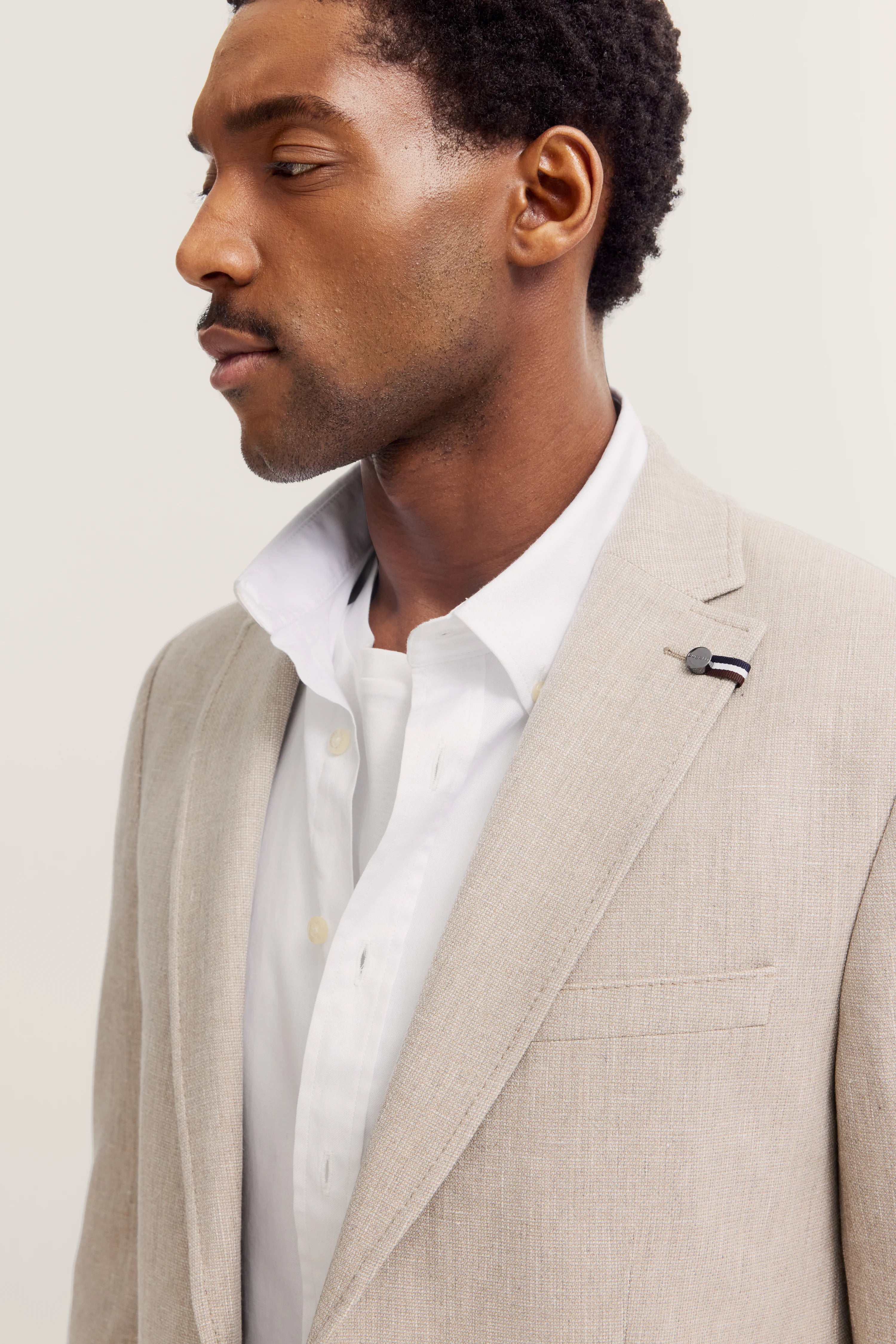 Beigefarbener bugatti-Blazer und weißes Hemd, Modelbild im Profil.