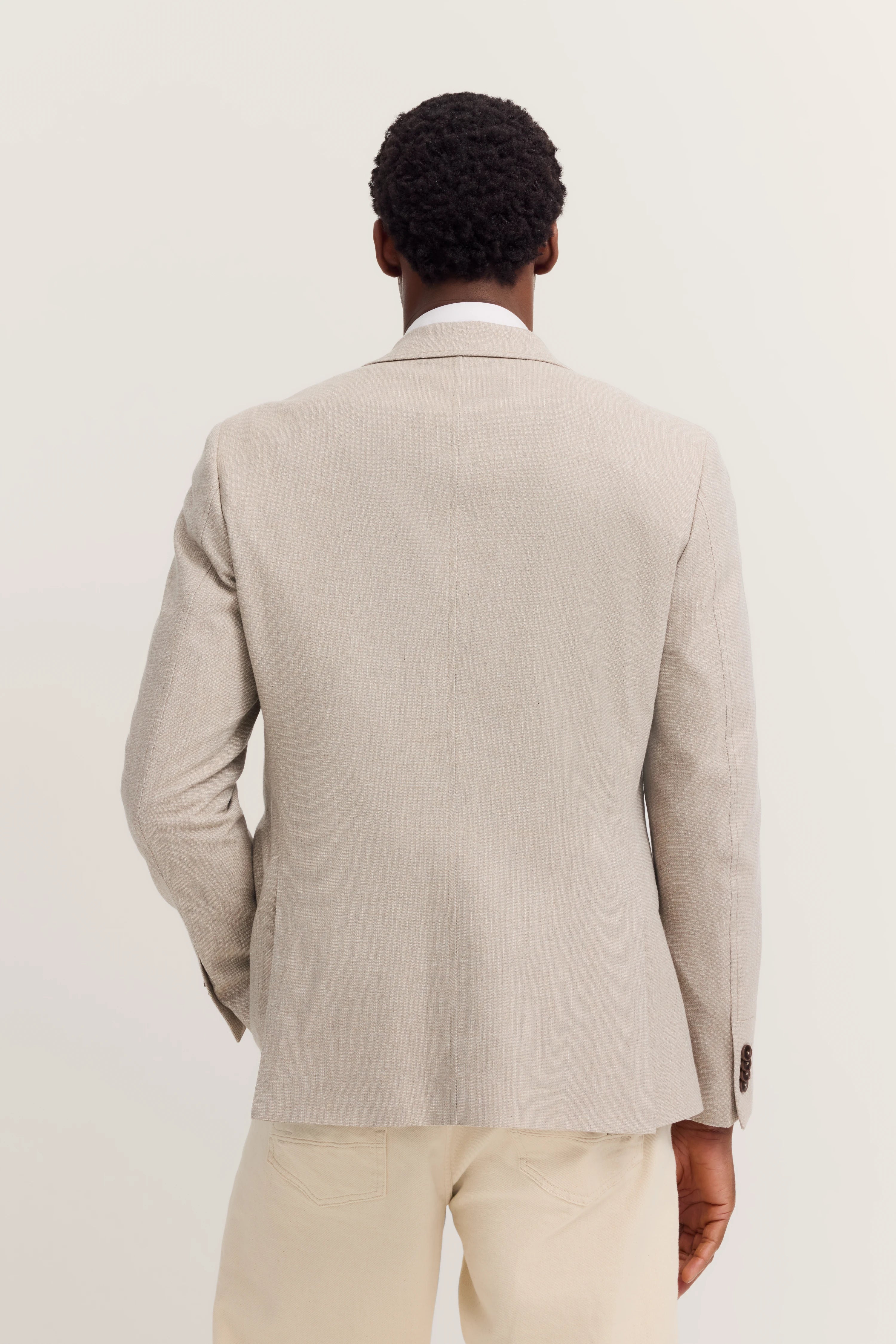 Beiger bugatti Blazer von hinten auf Model, kombiniert mit heller Hose, legeres Standing.