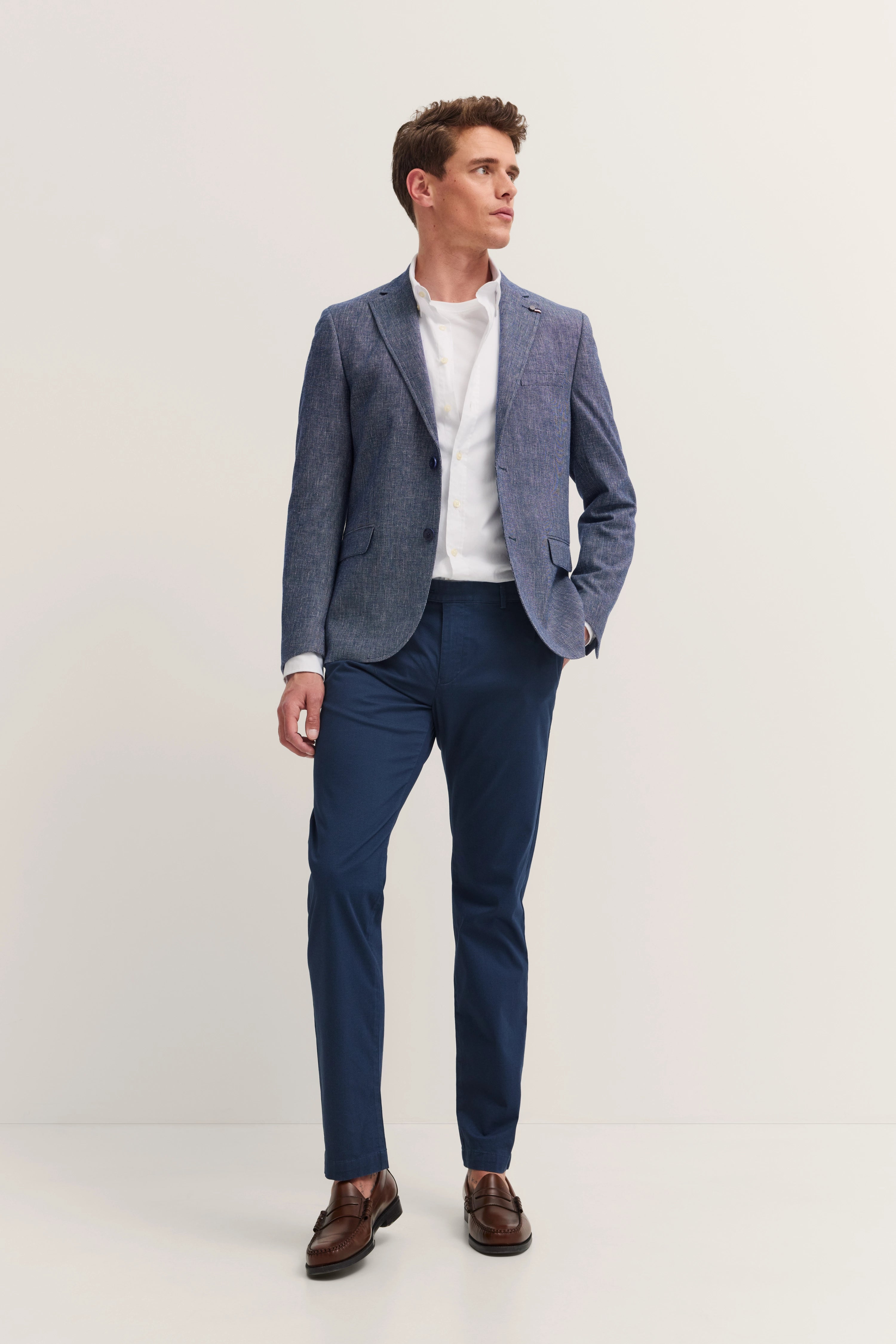 Model in blue bugatti suit with white shirt, elegant pose, brown shoes.
