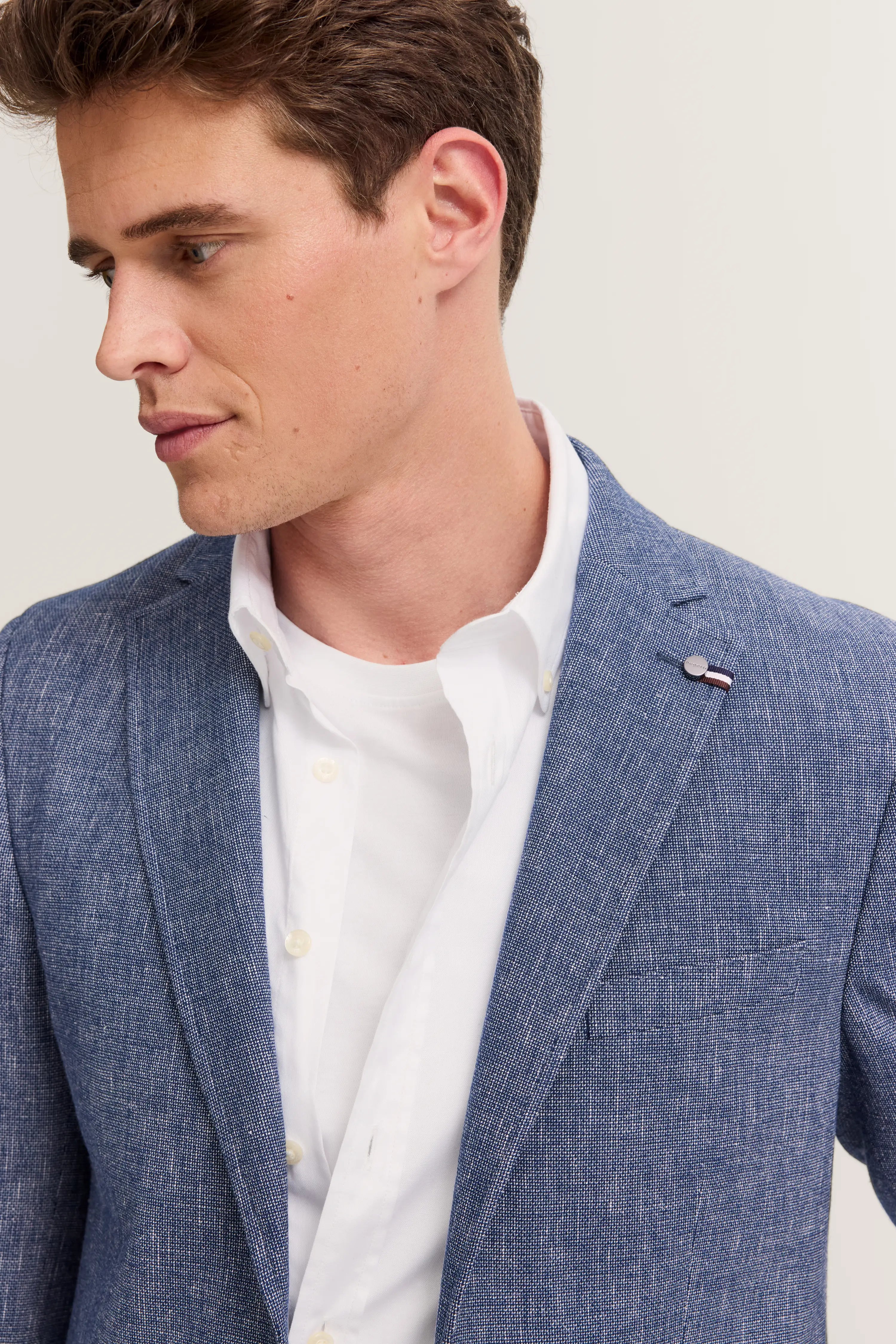 Blue bugatti blazer with white shirt, casual model looking sideways, exuding relaxed elegance.