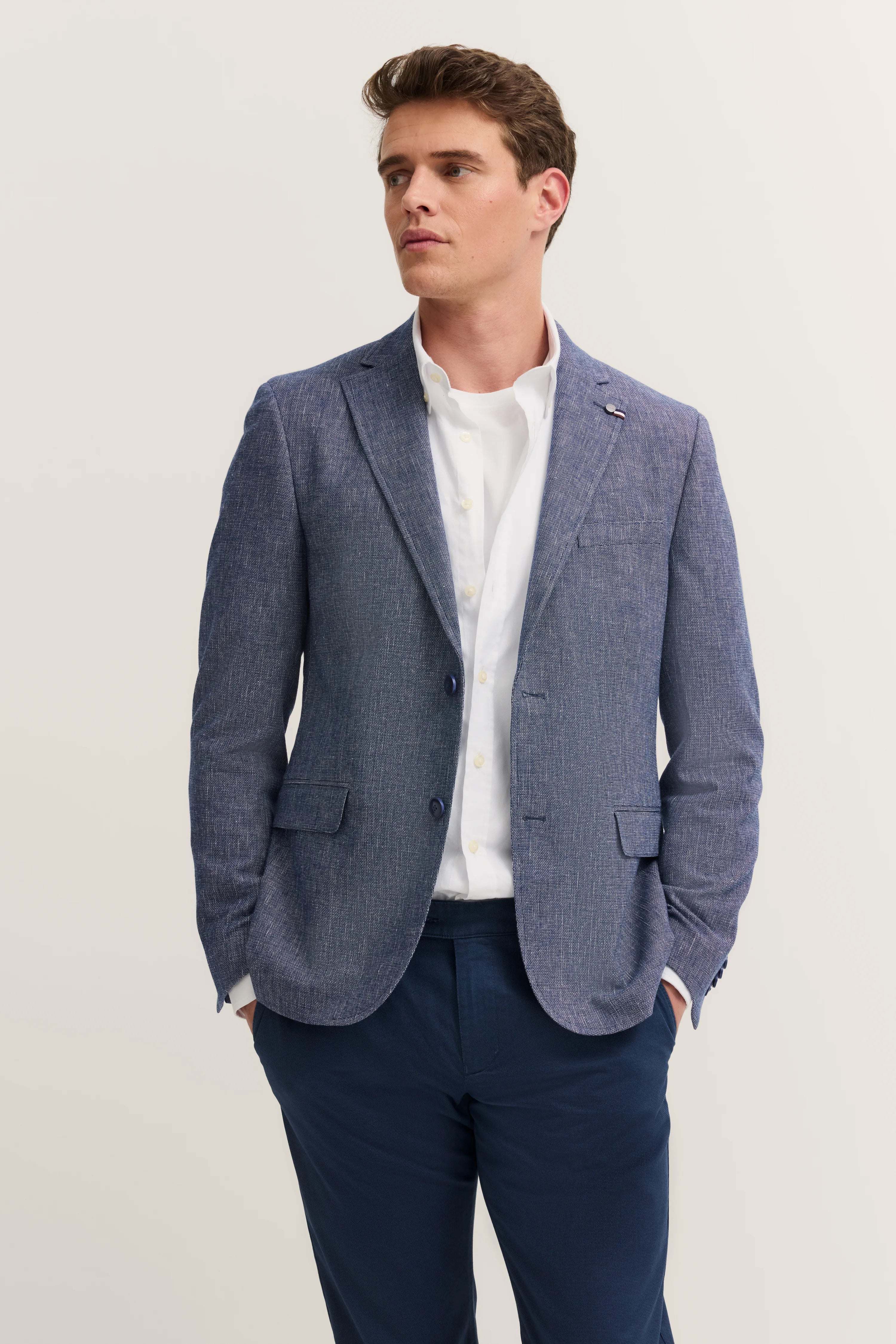 bugatti model image: blue blazer, white shirt, blue pants, relaxed pose, exuding Italian elegance and sophistication.