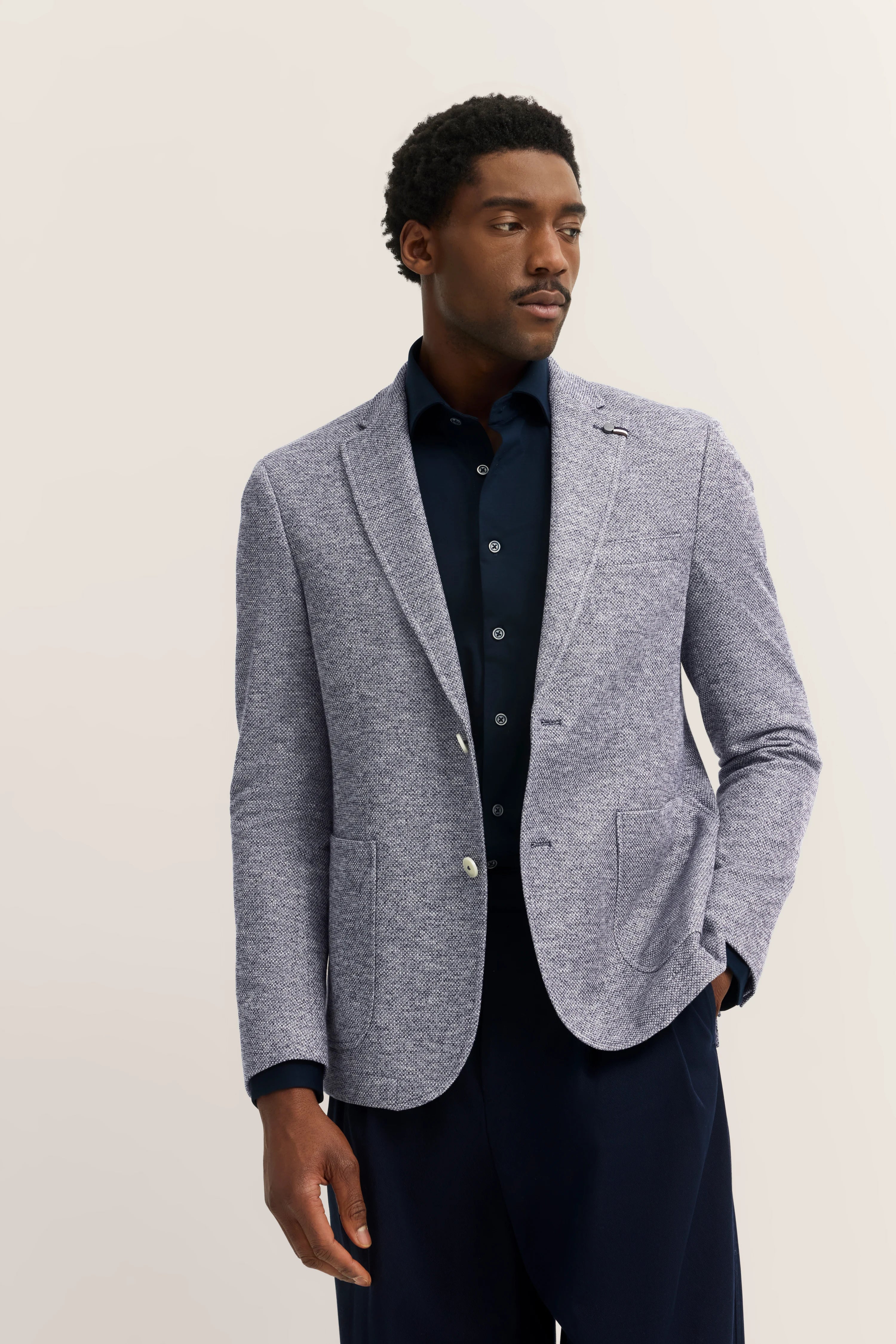 Model in gray bugatti blazer with navy shirt, casually posing.