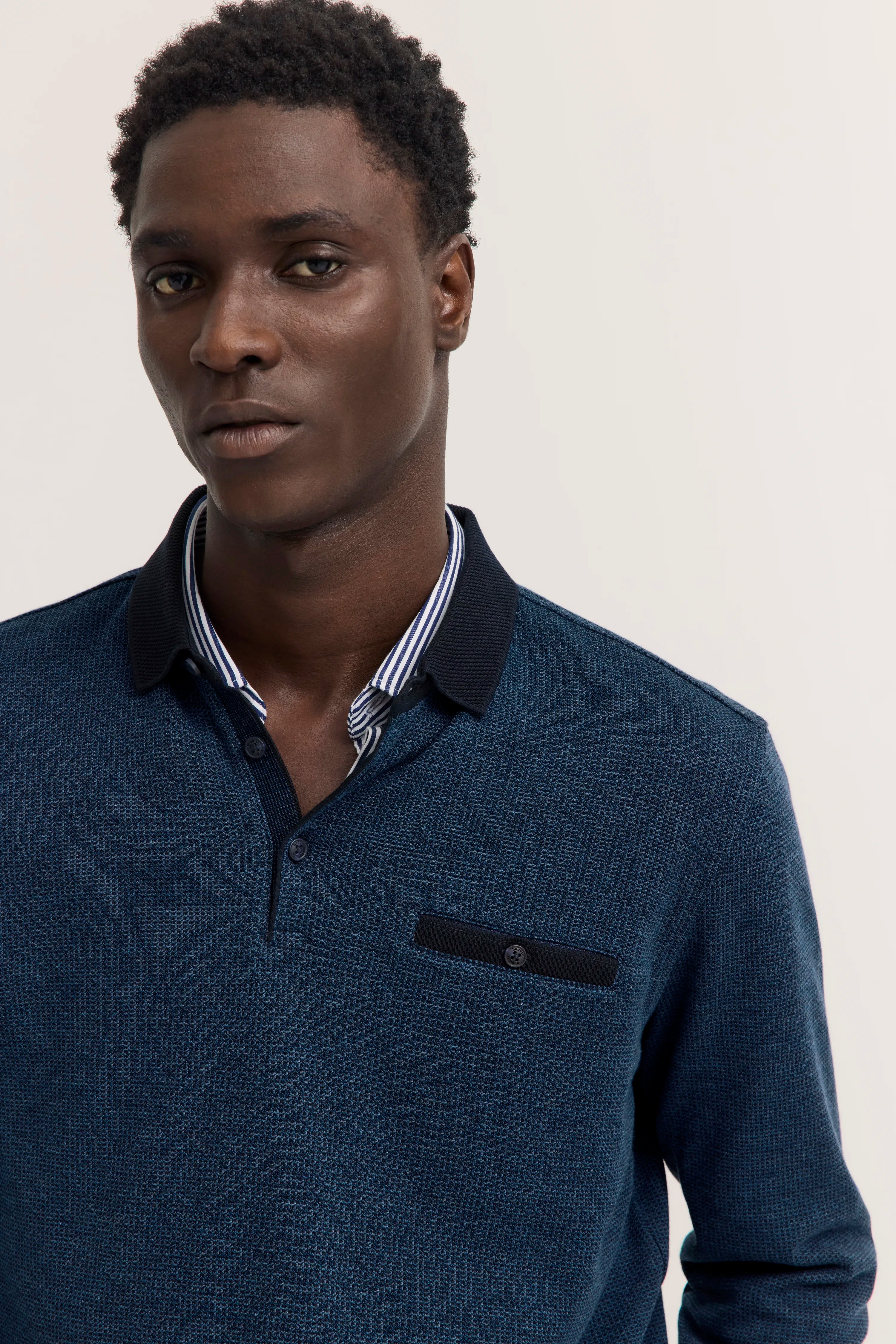 Model in bugatti Pullover, dunkelblau mit schwarzem Kragen, legeres Posing, hochwertige Details.