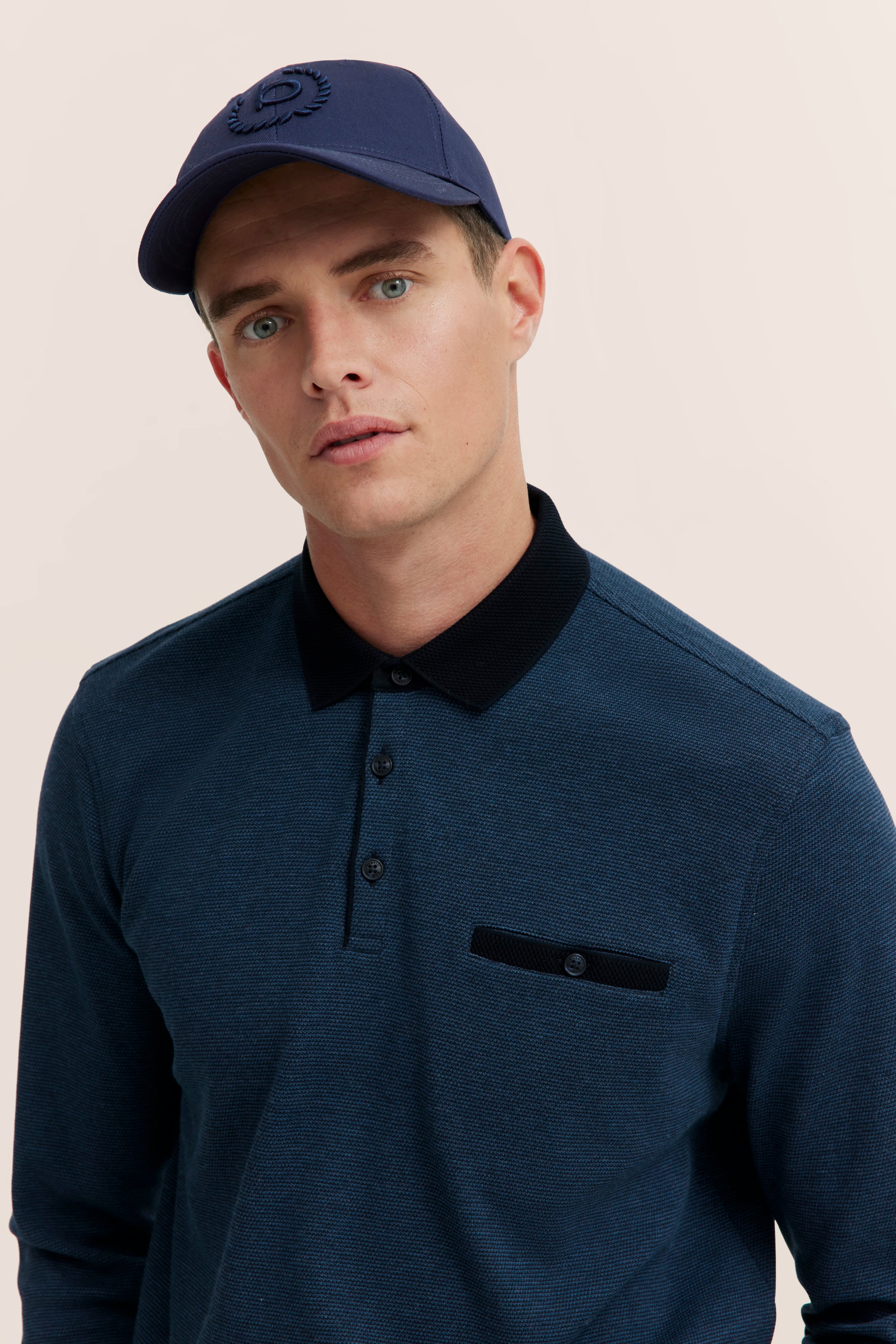 bugatti model in blue polo shirt and cap, relaxed pose.