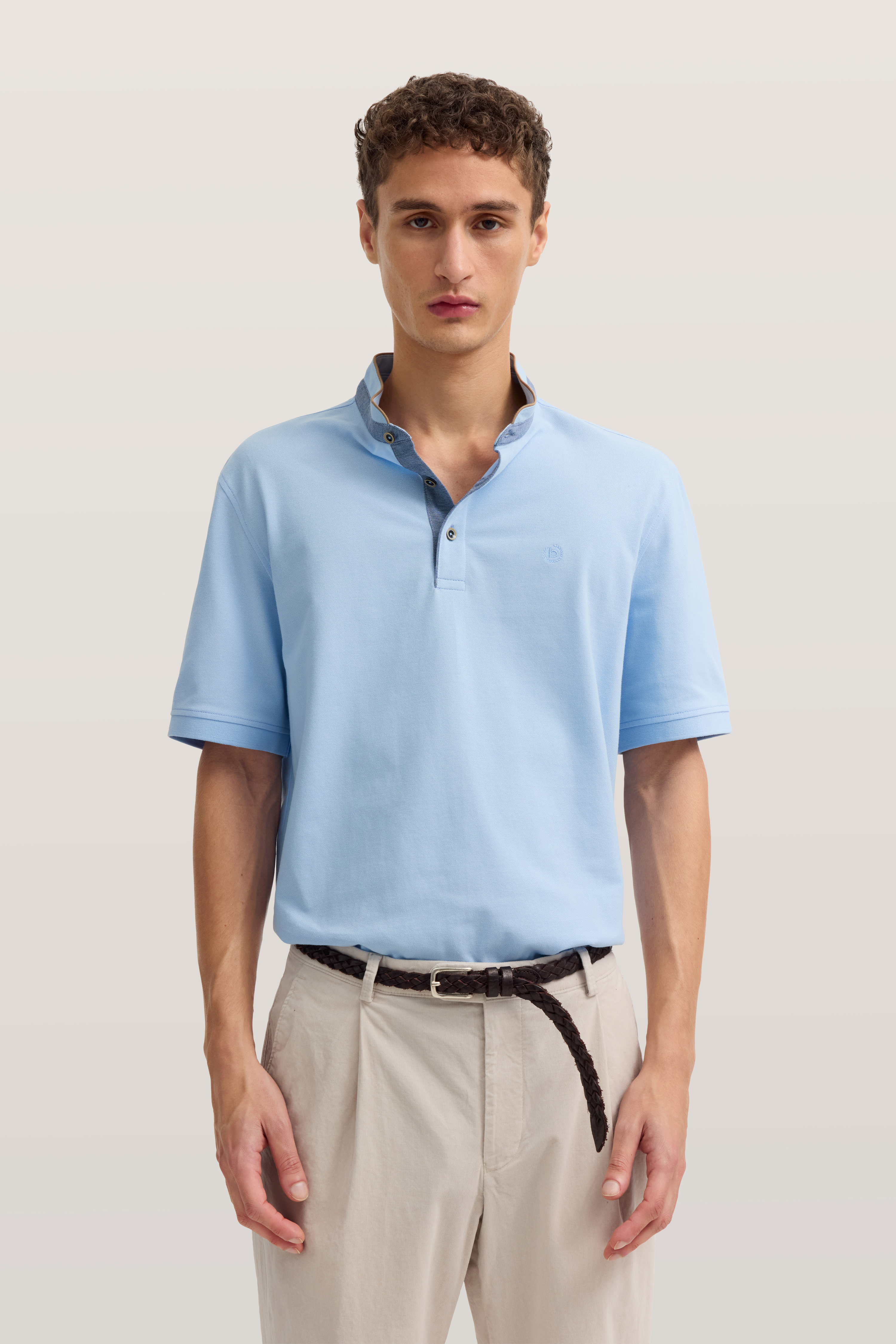 bugatti Modelbild: Mann in hellblauem Polo und beigen Hosen, frontal stehend, entspannte Pose.