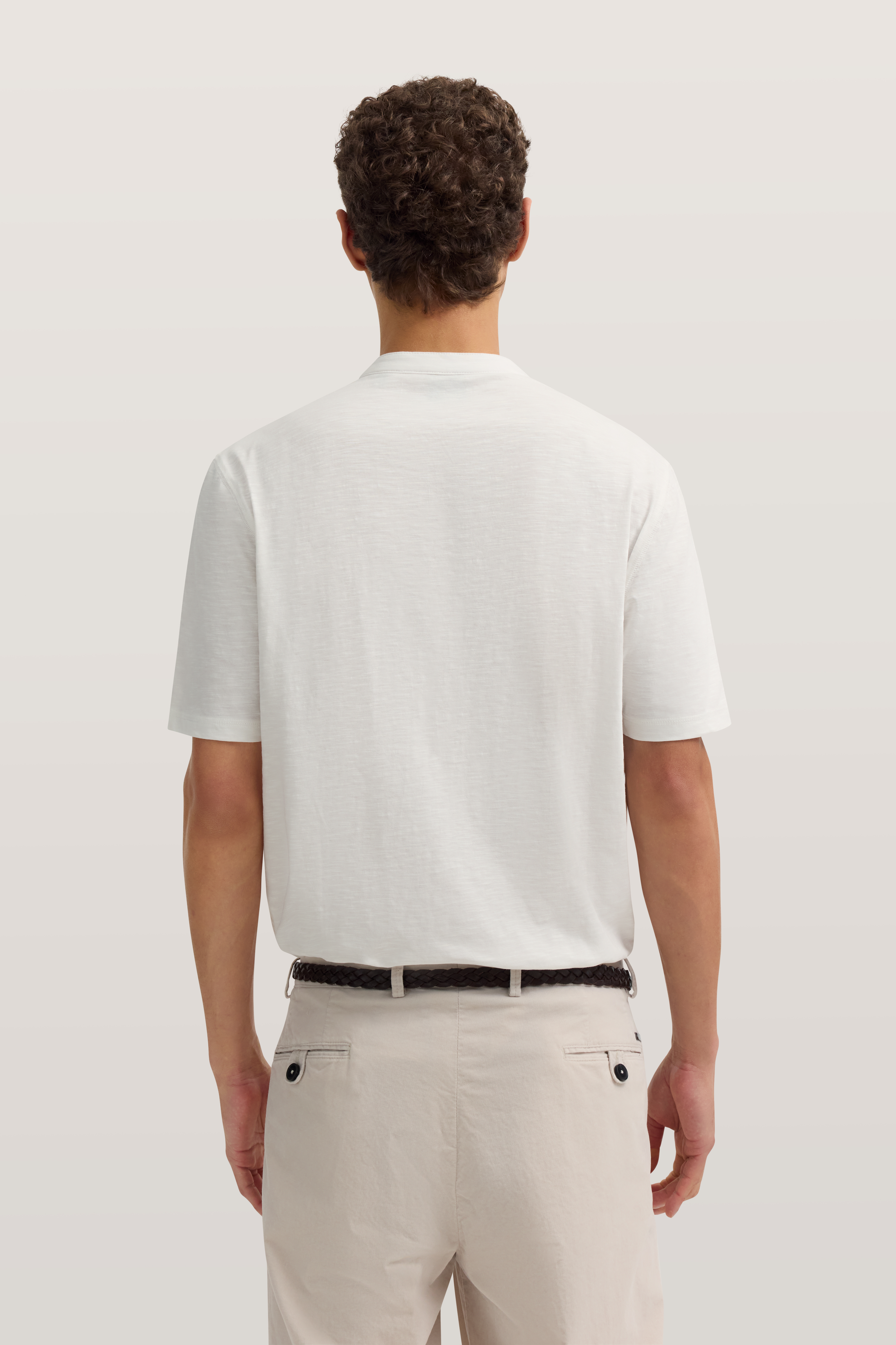 Weiße T-Shirt und beige Chino-Hose Rückansicht, Model stehend.