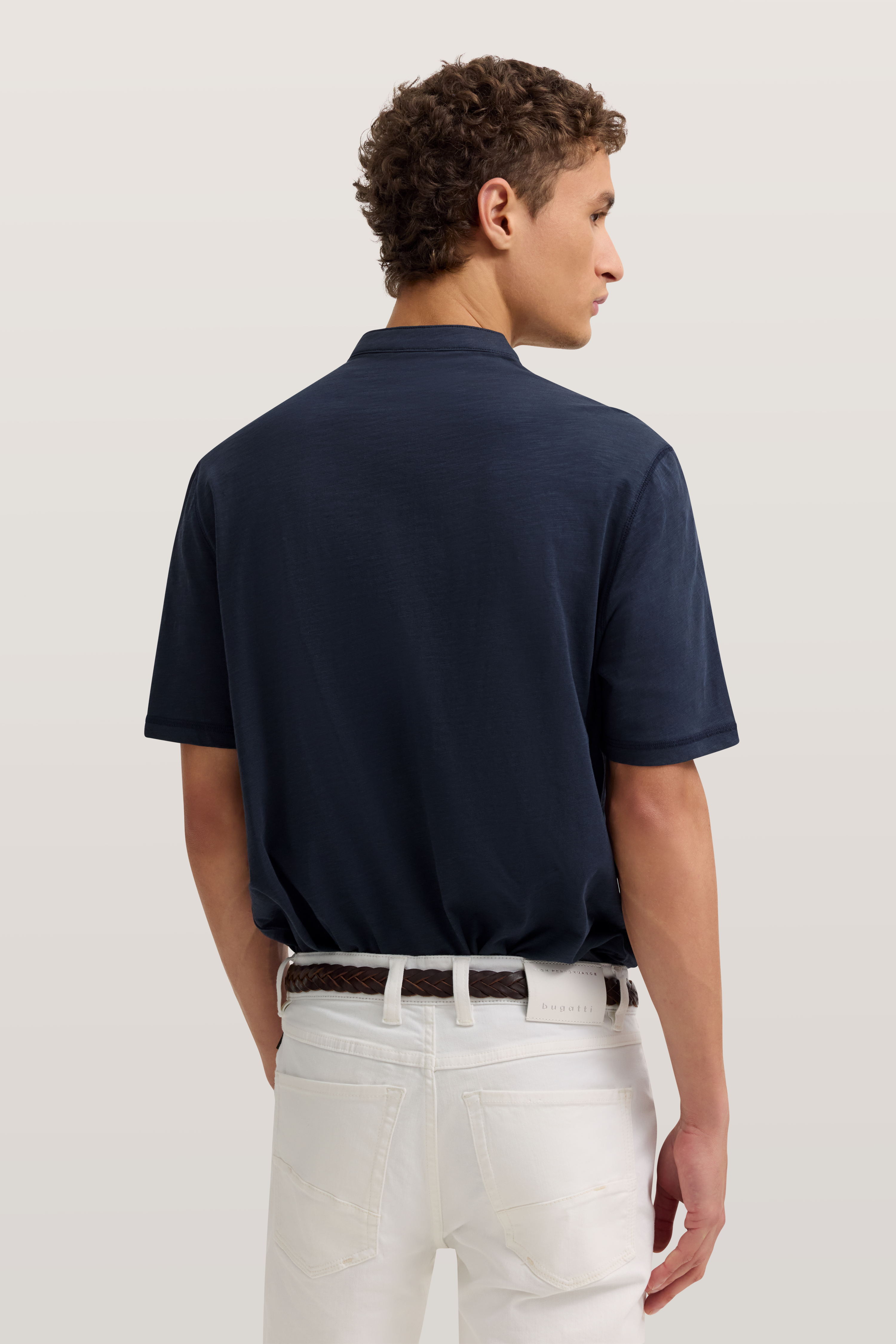 Navy Polo und weiße Hose von bugatti, Model von hinten, casual Pose.