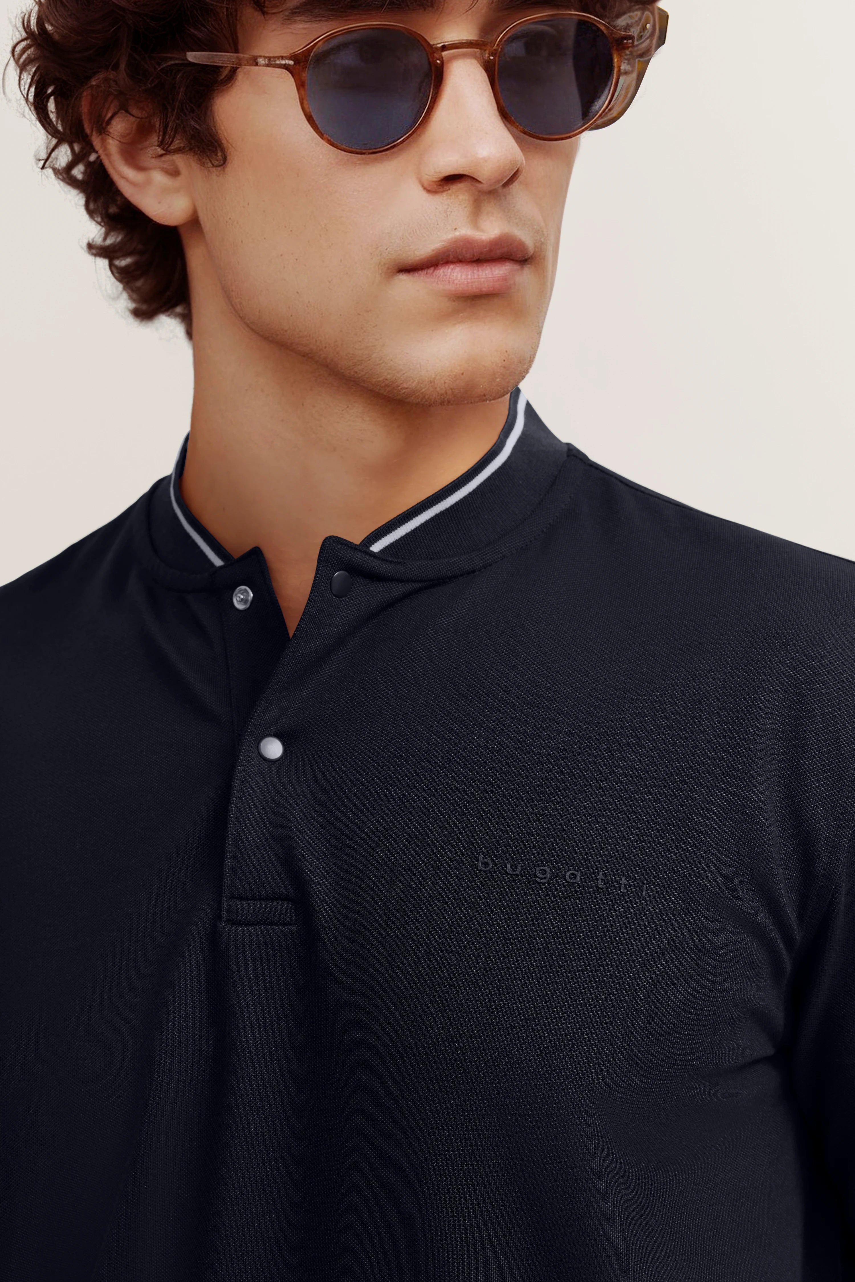 Ein Model trägt ein schwarzes bugatti Poloshirt, klassisches Design, legerer Look.