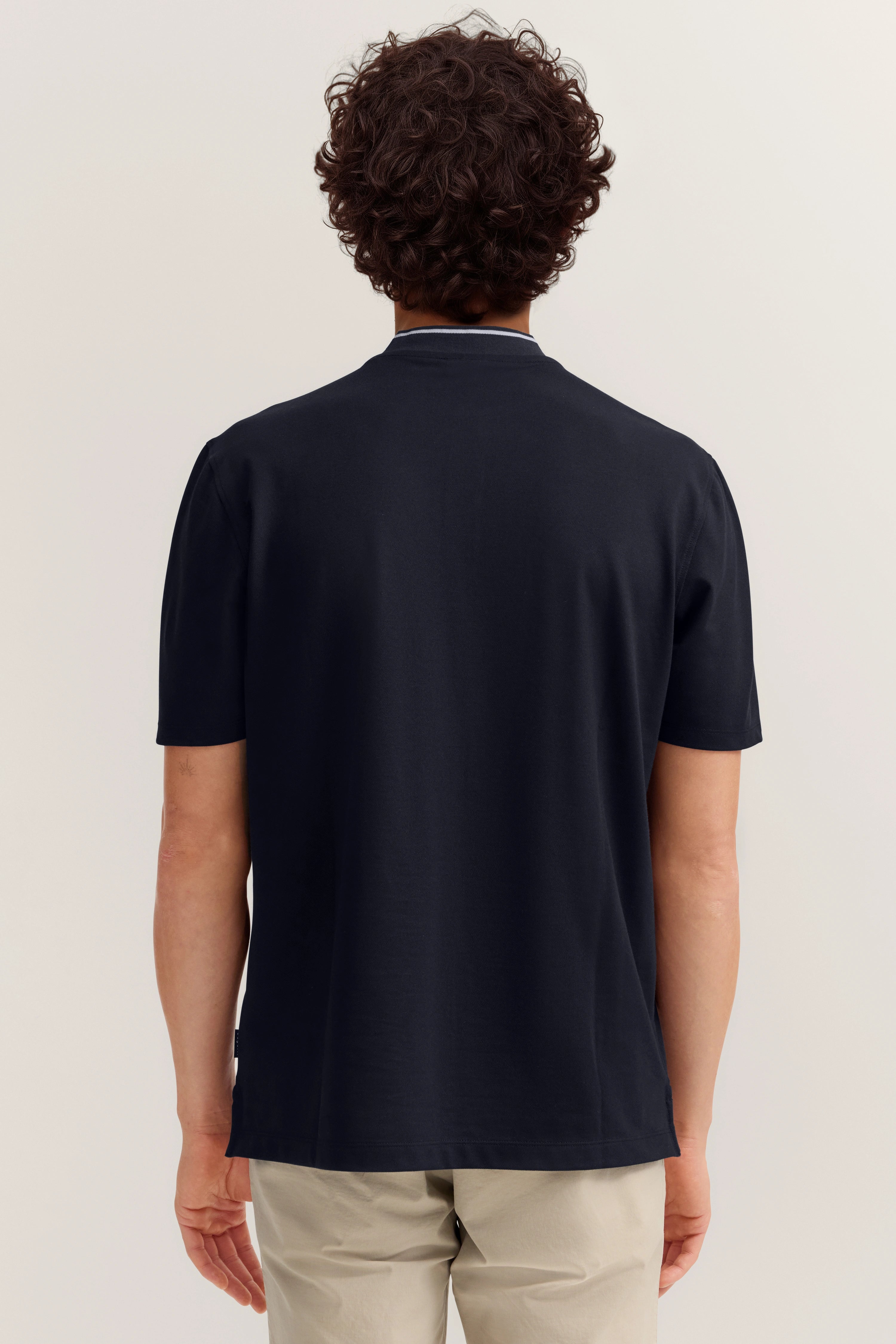 Rückenansicht: Dunkelblaues bugatti T-Shirt, beige Hose, legeres Modelbild.