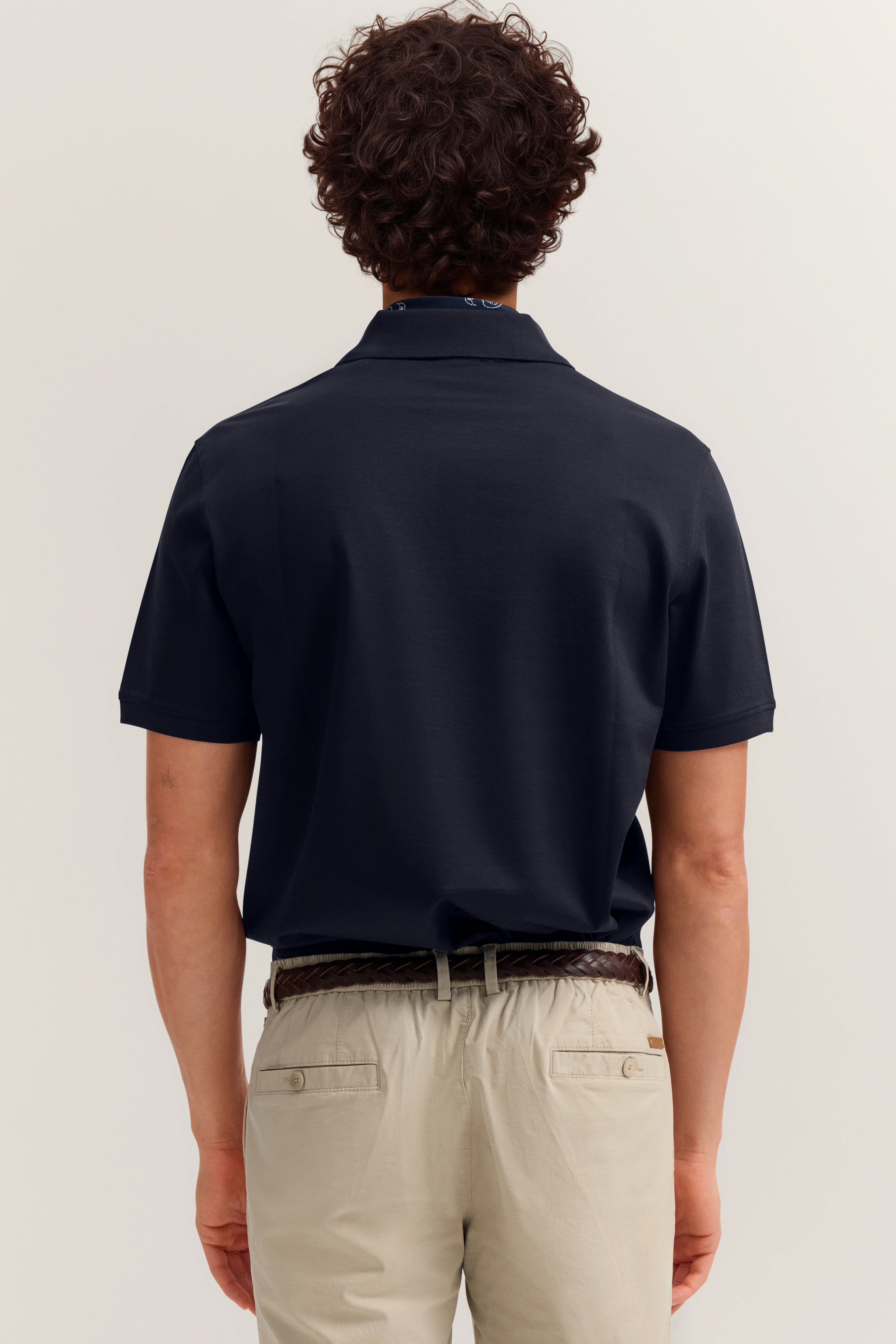 Alt-Text: Model in navy bugatti Poloshirt und beigen Chinos, Rückenansicht, entspanntes Posing.