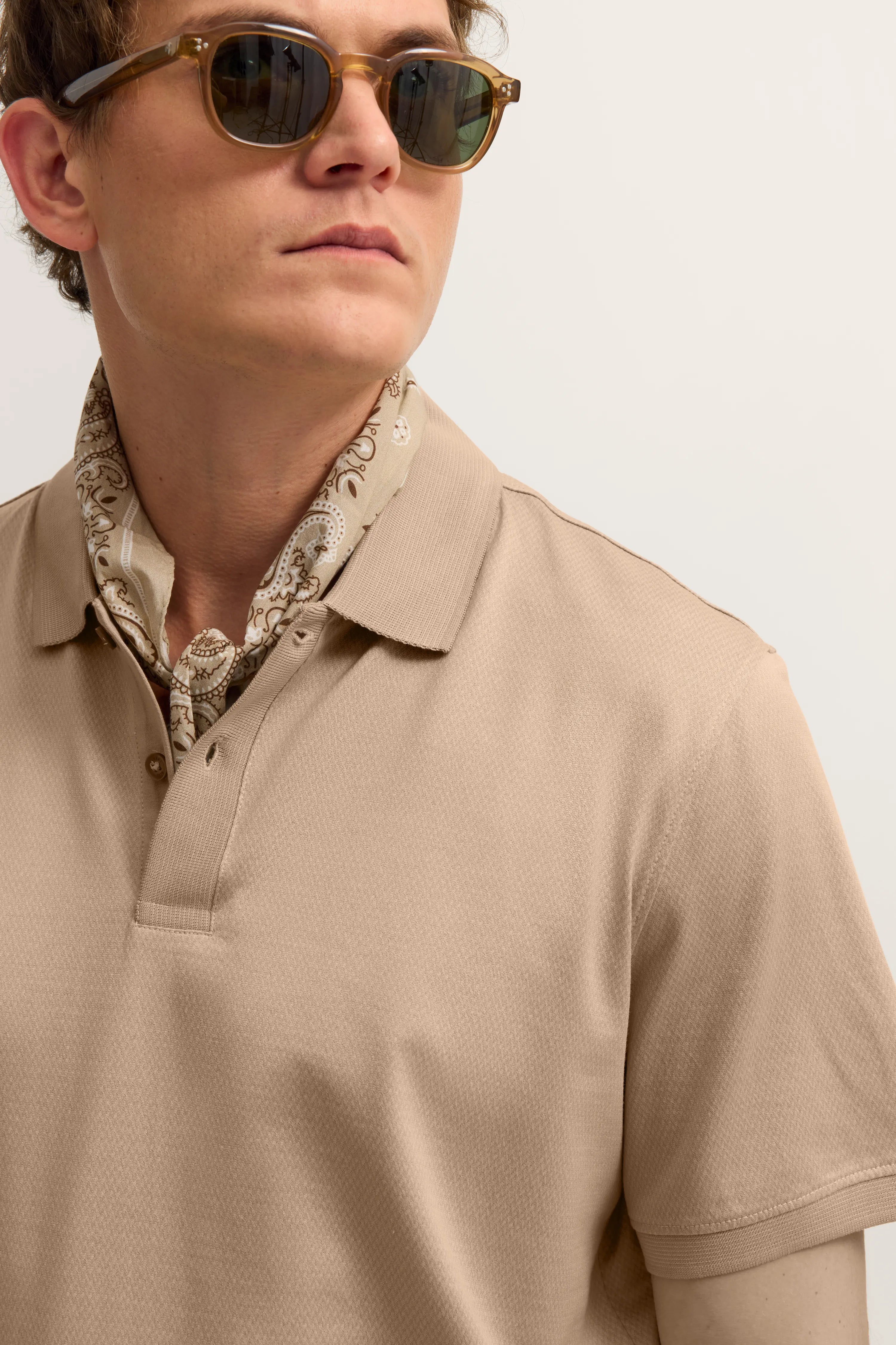 Beige Polo und Leinenhose, Rückansicht, legeres Modelbild, entspannte Haltung.