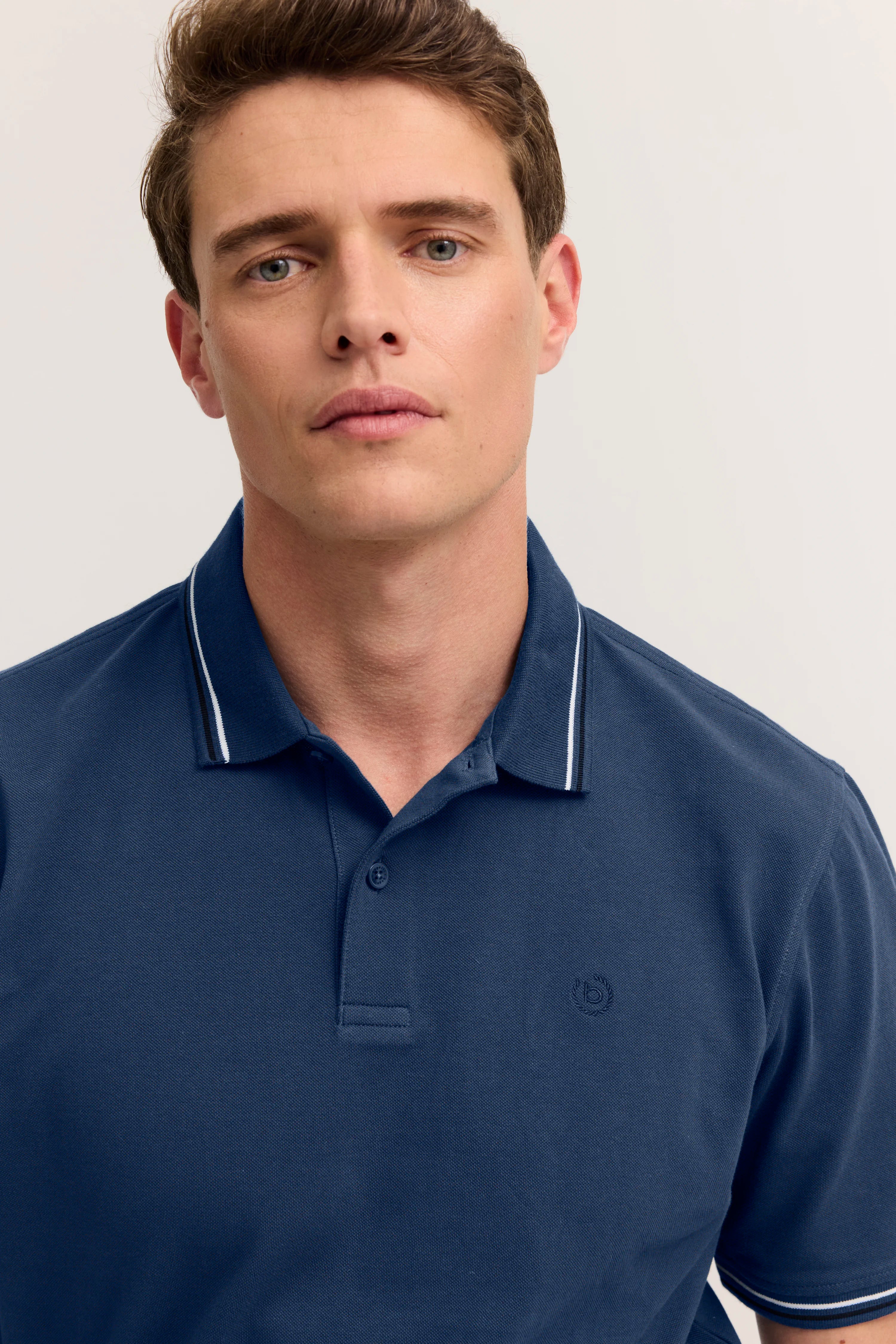 Navy Poloshirt mit weißen Streifen am Kragen, Modelbild, entspannter Gesichtsausdruck