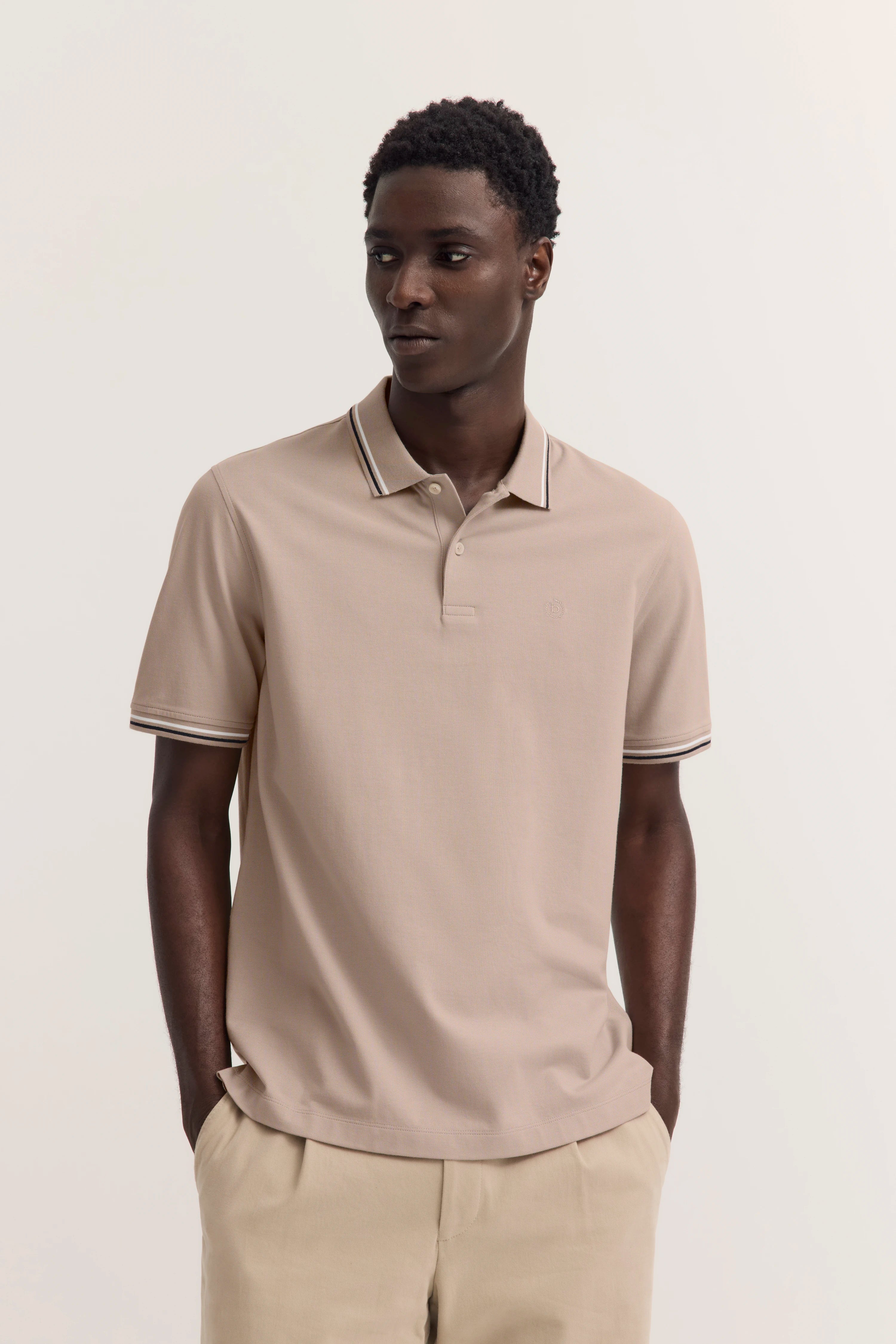 Beiges Polohemd von bugatti, legeres Modelbild, Hände in Taschen, entspannter Look.