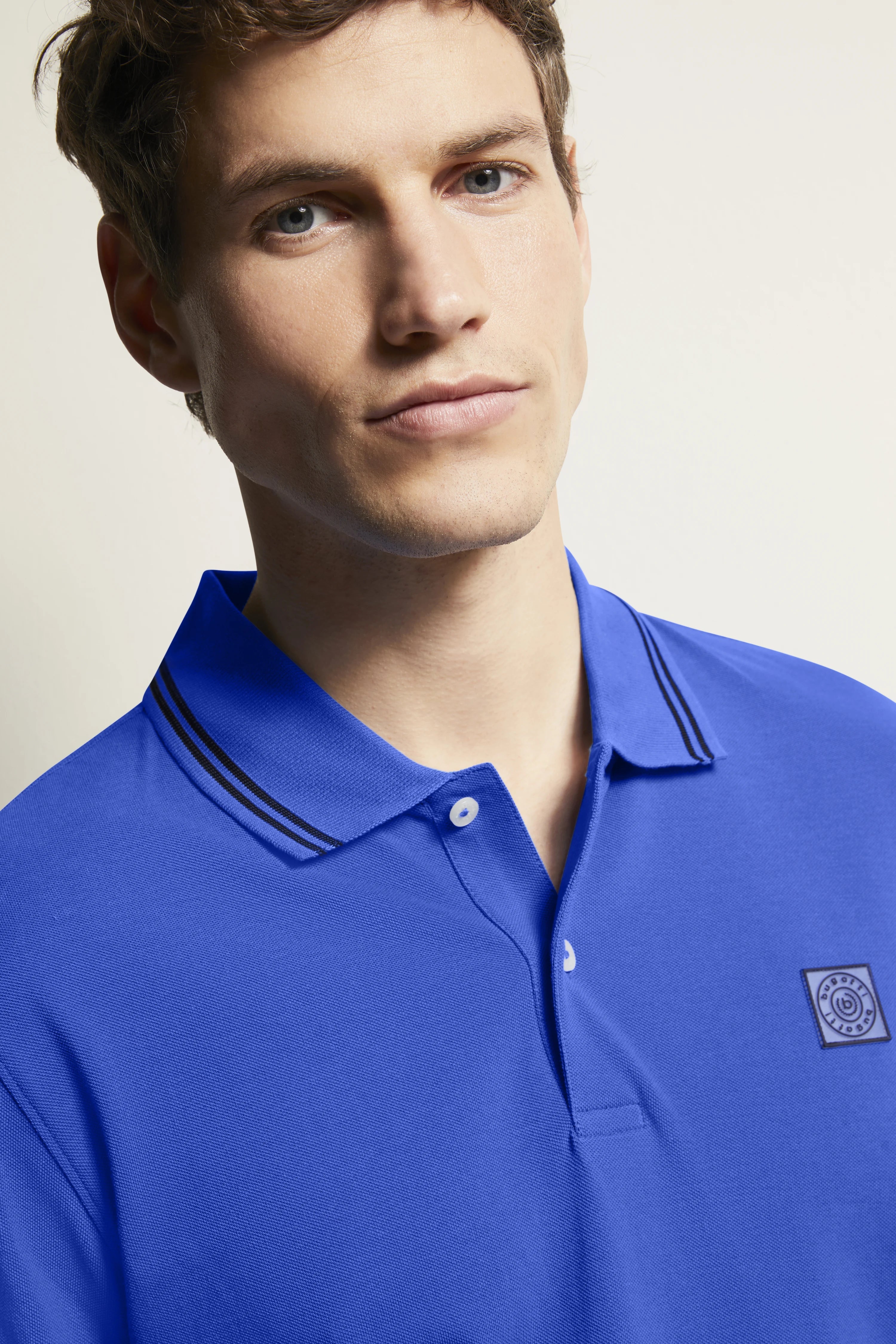 Blue bugatti polo shirt, model close-up, relaxed pose.
