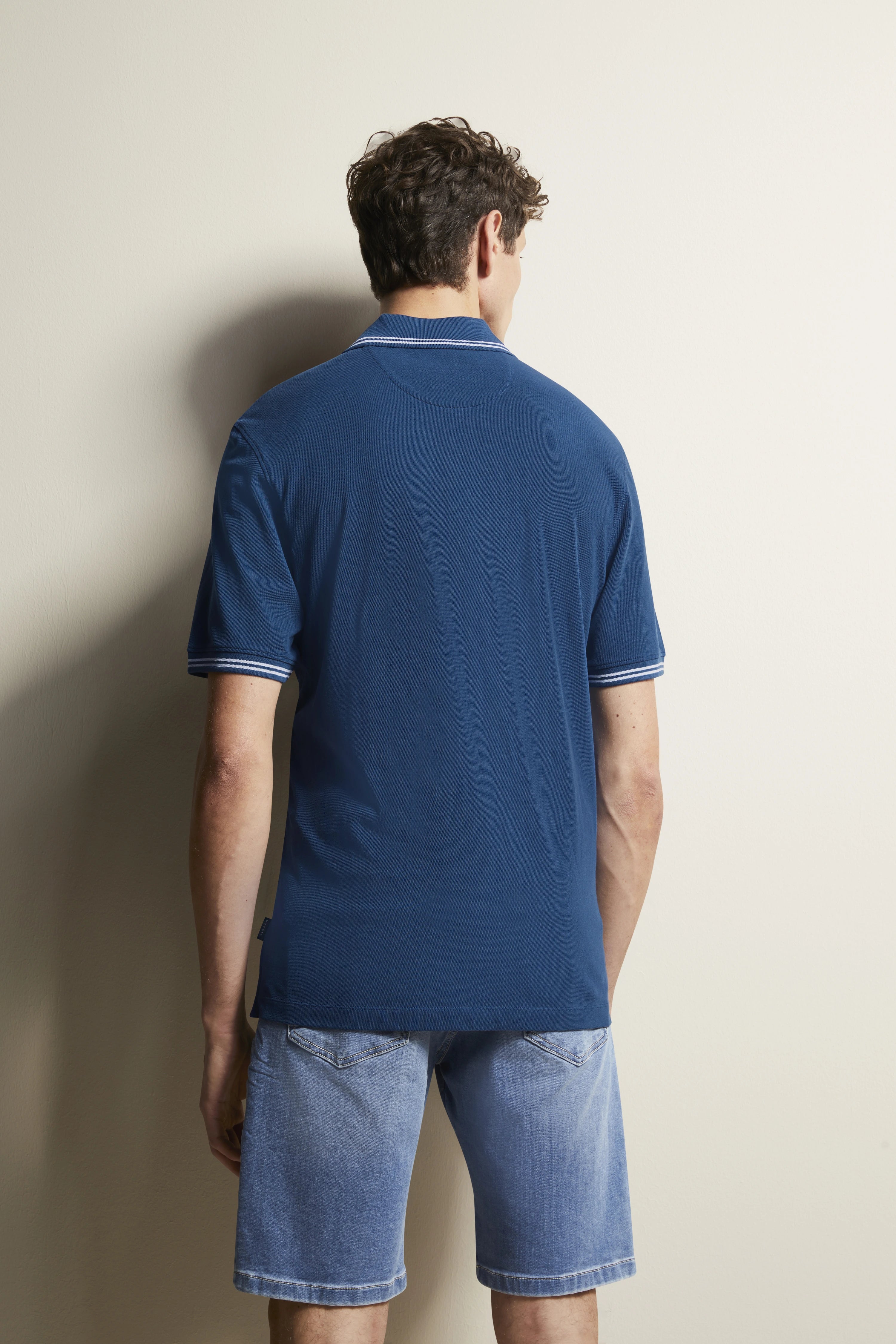 bugatti model: Man in blue polo, jeans shorts, back view, casual pose, elegance and effortless style.
