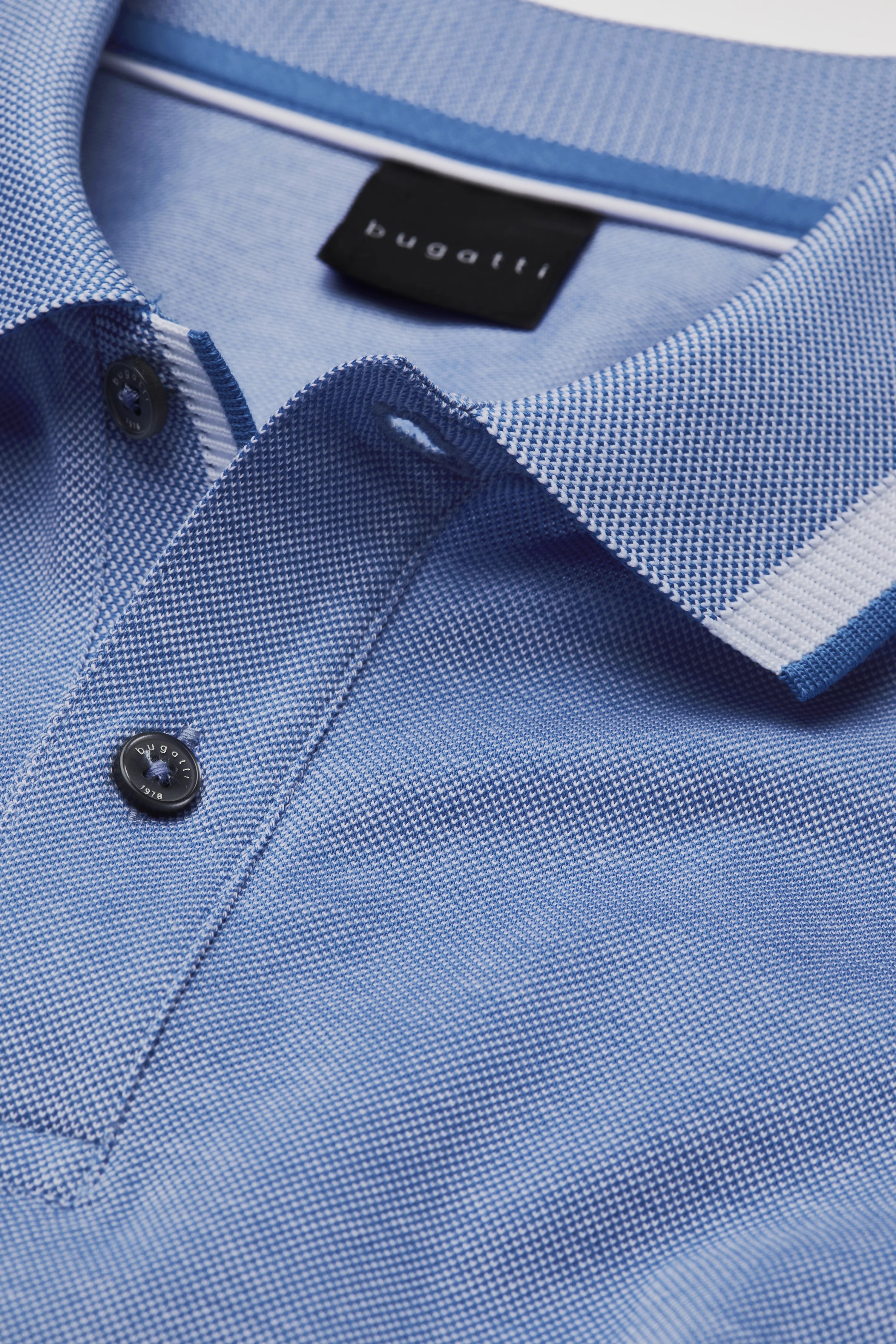 Blue bugatti polo shirt close-up with fine texture and button closure.