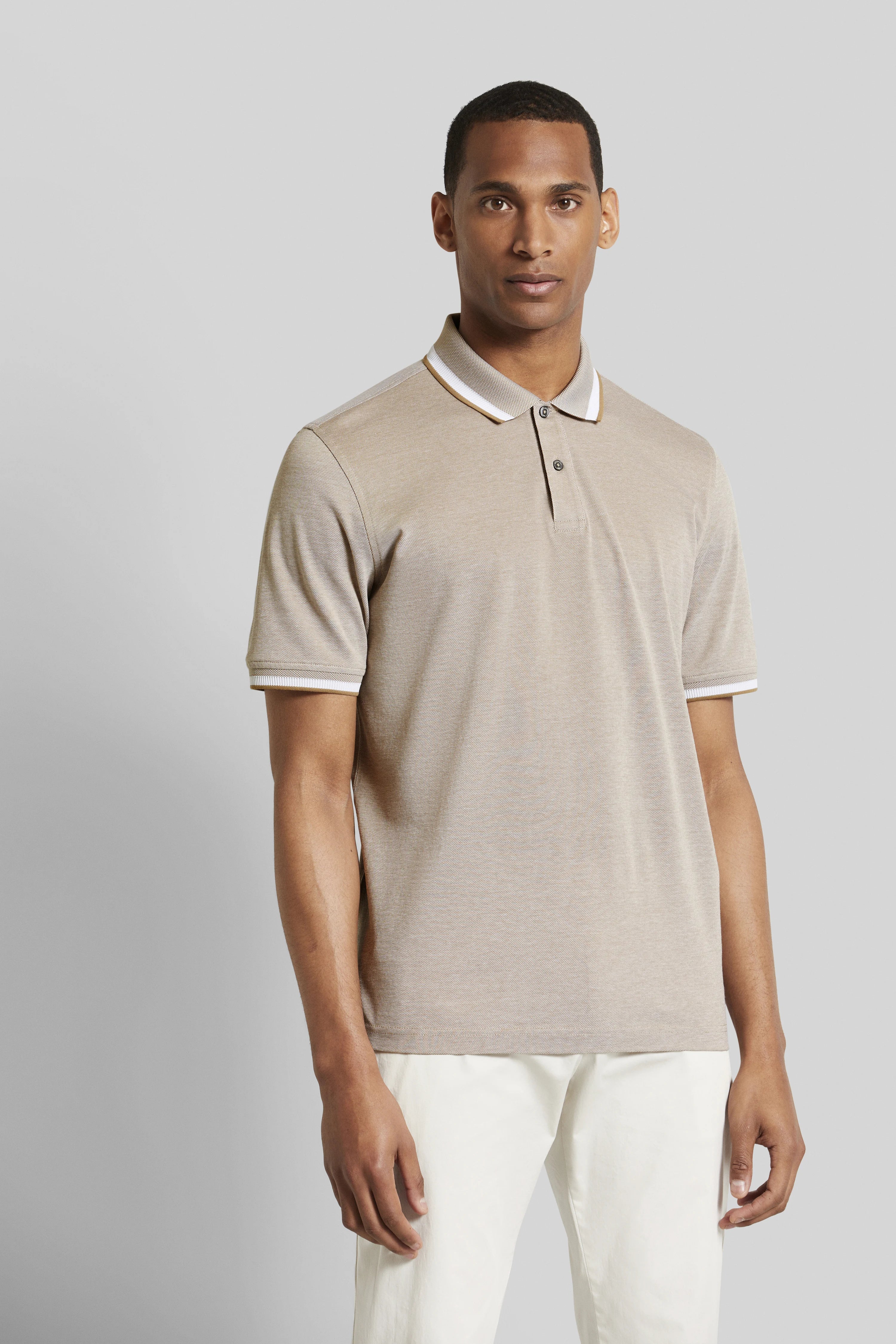 Beiges Polohemd von bugatti, getragen von einem Modell, kombiniert mit weißen Hosen, lässiges Posing.